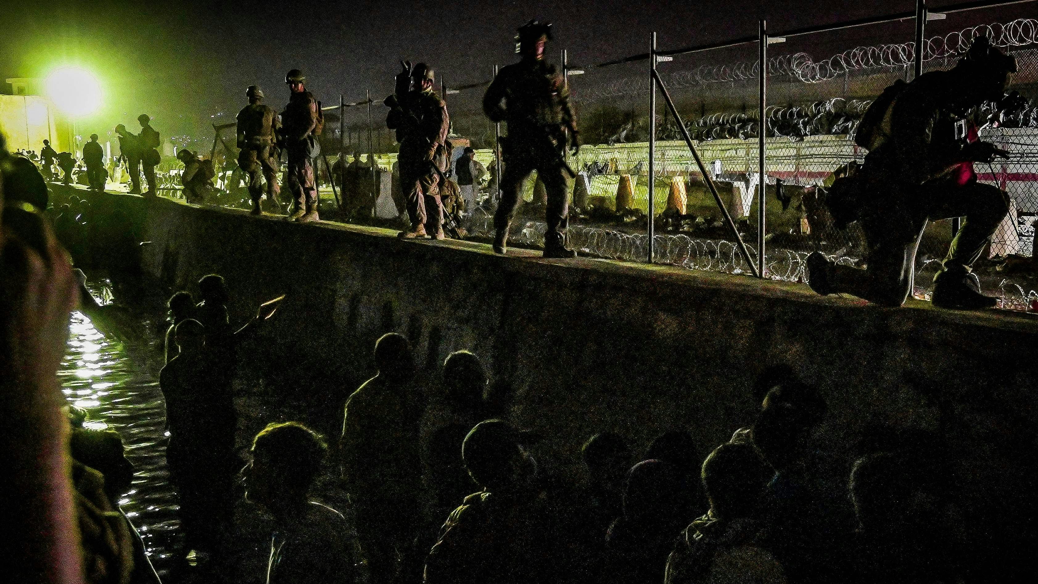 Download von www.picturedesk.com am 23.08.2021 (08:29).  In this picture taken in the late hours on August 22, 2021 British and Canadian soldiers stand guard near a canal as Afghans wait outside the foreign military-controlled part of the airport in Kabul, hoping to flee the country following the Taliban's military takeover of Afghanistan. (Photo by WAKIL KOHSAR / AFP) - 20210823_PD0442 - Rechteinfo: Rights Managed (RM) Nur für redaktionelle Nutzung! Werbliche Nutzung erfordert Freigabe: bitte schicken Sie uns eine Anfrage.