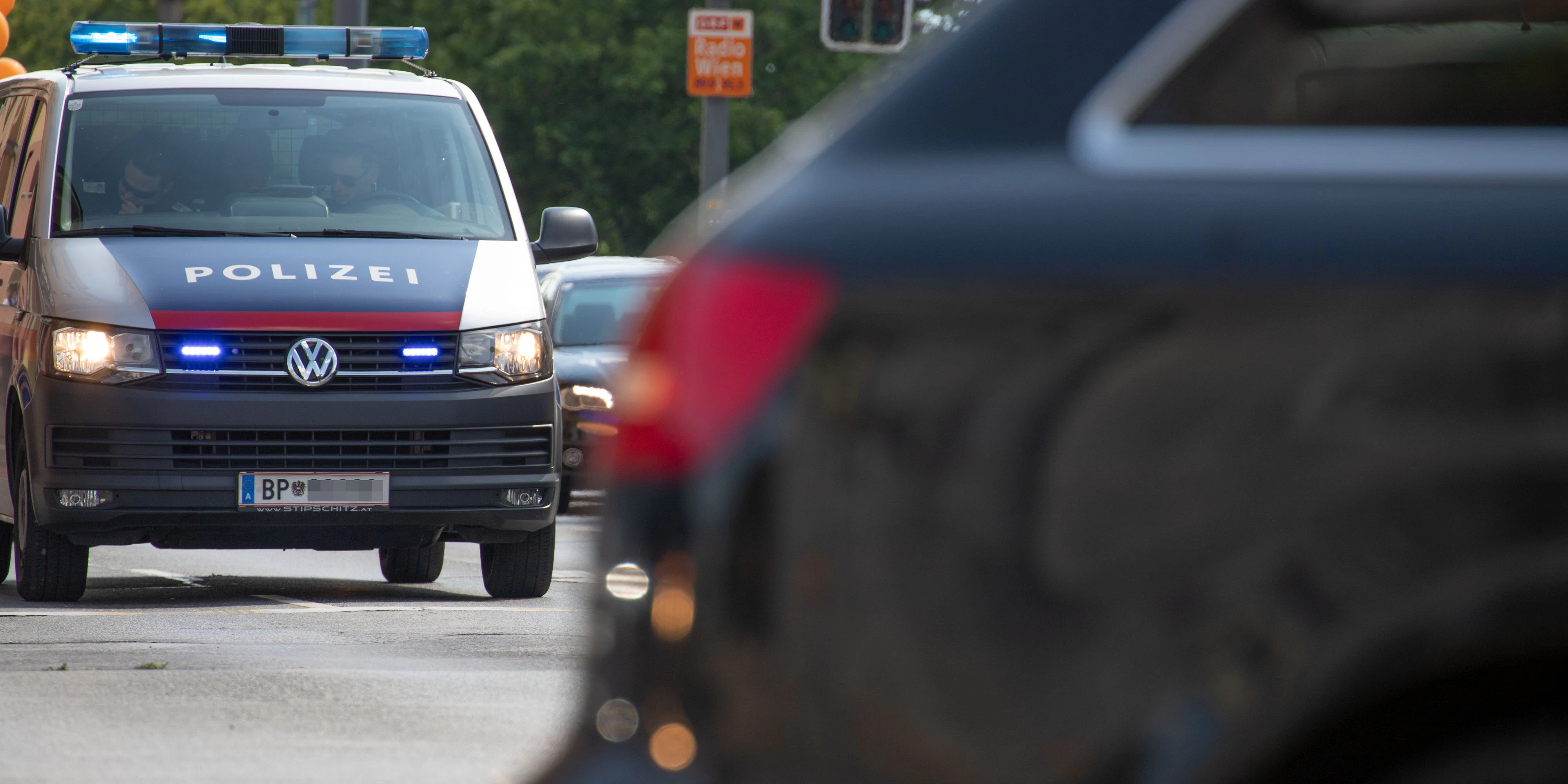 Bus der Wiener Polizei fährt mit eingeschaltetem Blaulicht auf einer stark befahrenen Straße in Wien