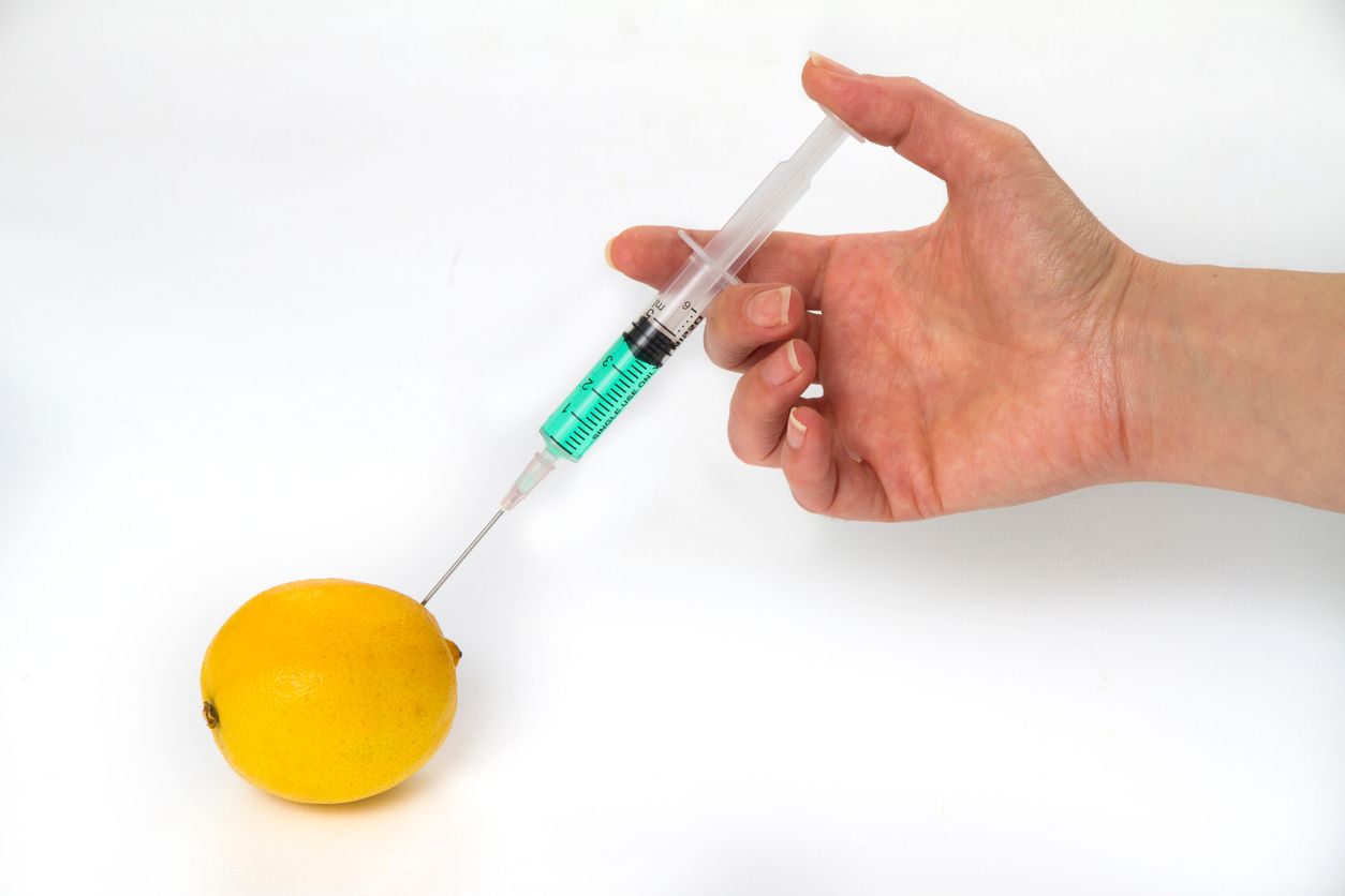A hand inject with a syringe into lemon