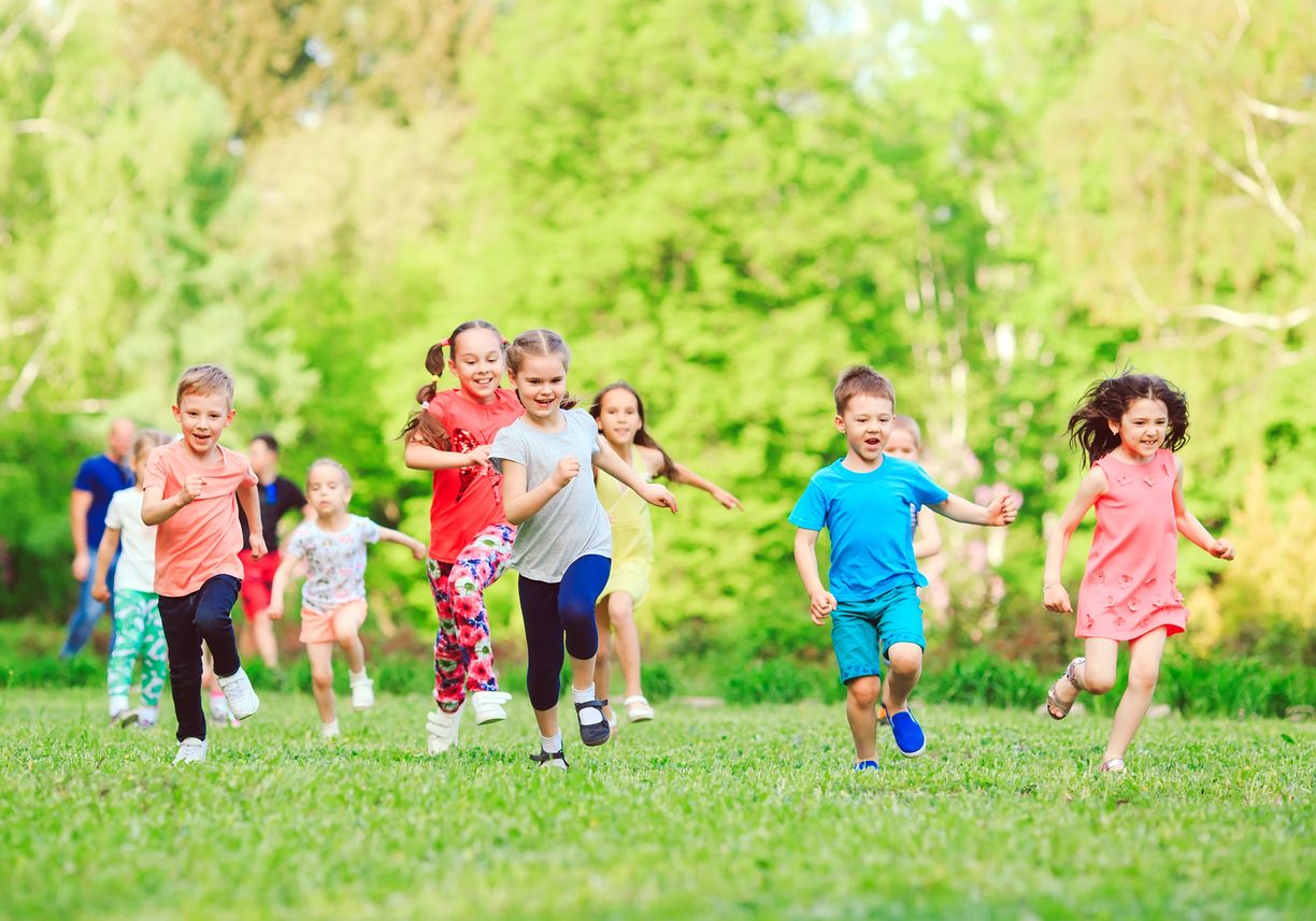 Many different kids, boys and girls running in the park on sunny summer day in casual clothes