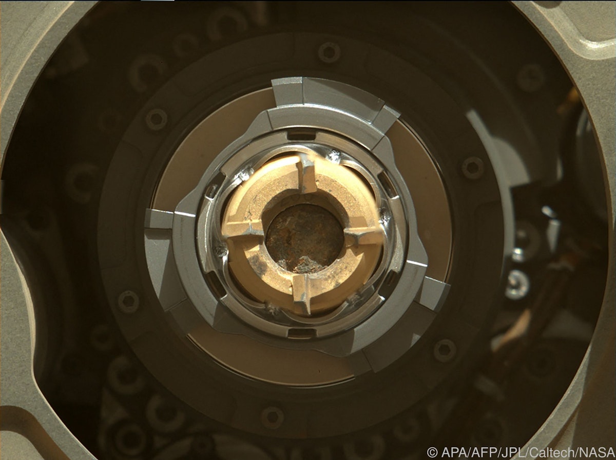 In this image released by NASA Perseverance rover shows a sample tube with its cored-rock contents inside, the bronze-colored outer-ring is the coring bit, the lighter-colored inner-ring is the open end of the tube, and inside is a rock core sample slightly thicker than a pencil, September 1, 2021. - NASA's Perseverance rover succeeded in its second attempt to scoop up a piece of Martian rock for future analysis by scientists on Earth -- probably..Its first effort earlier this month failed after the rock was too crumbly to withstand the robot's drill, but data received late on September 1 indicates the process worked..The US space agency said Thursday it remains a little uncertain, because images taken after the rover's arm completed sample acquisition were inconclusive due to poor sunlight conditions..More images taken under better lighting are expected back by Saturday.."The team determined a location, and selected and cored a viable and scientifically valuable rock," said Jennifer Trosper, project manager at NASA's Jet Propulsion Laboratory in Pasedena.."We will work through this small hiccup with the lighting conditions in the images and remain encouraged that there is sample in this tube.".The target was a briefcase-sized rock from a ridgleine that is half-a-mile (900 meters) long nicknamed "Rochette." (Photo by Handout / various sources / AFP) / RESTRICTED TO EDITORIAL USE - MANDATORY CREDIT "AFP PHOTO / NASA/JPL-Caltech" - NO MARKETING - NO ADVERTISING CAMPAIGNS - DISTRIBUTED AS A SERVICE TO CLIENTS