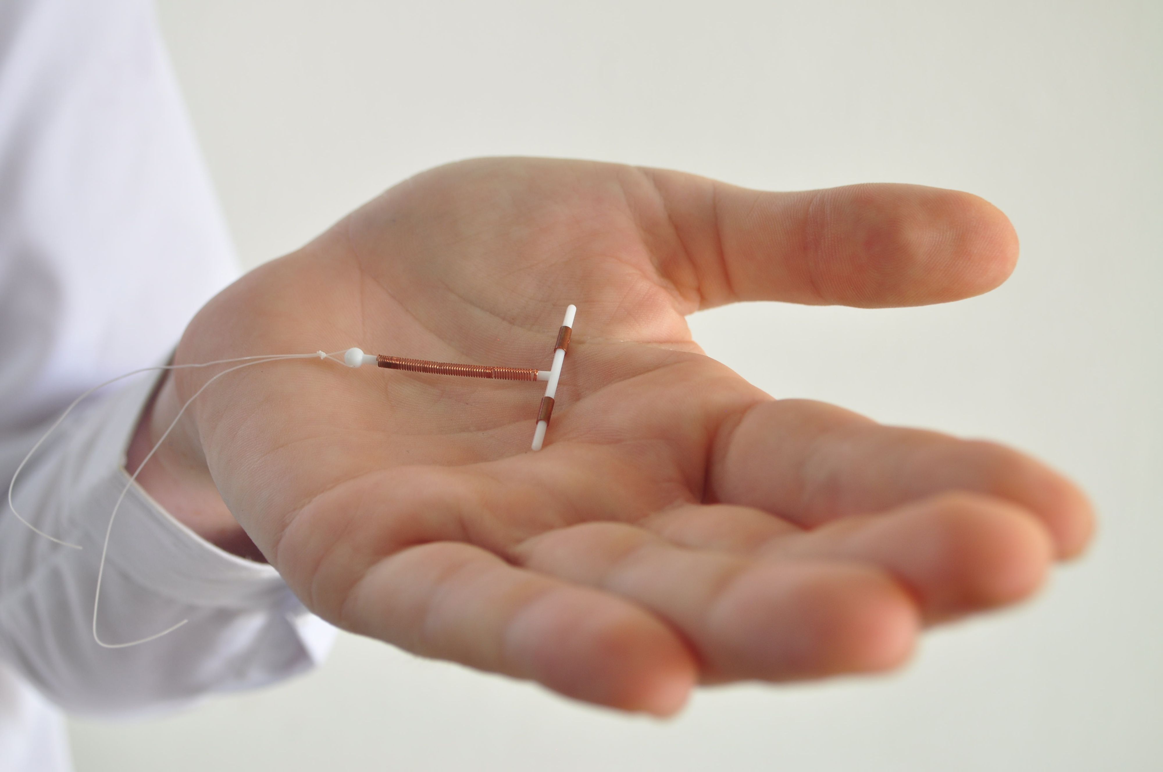 Holding an IUD birth control copper coil device in hand, used for contraception - side view