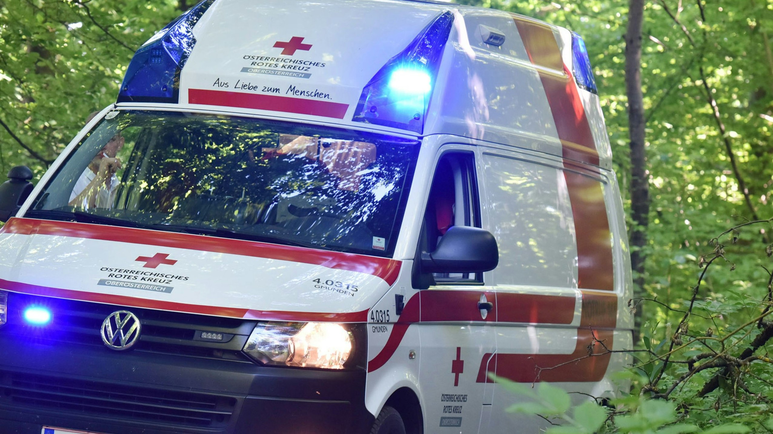 A red cross ambulance with blue lights in a wood, Austria, Europe