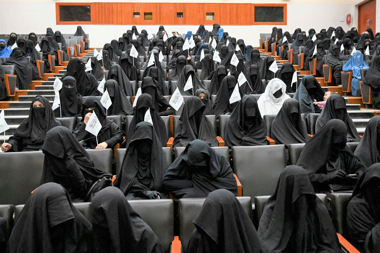 Verschleierte Frauen mit Taliban-Fähnchen im Uni-Saal