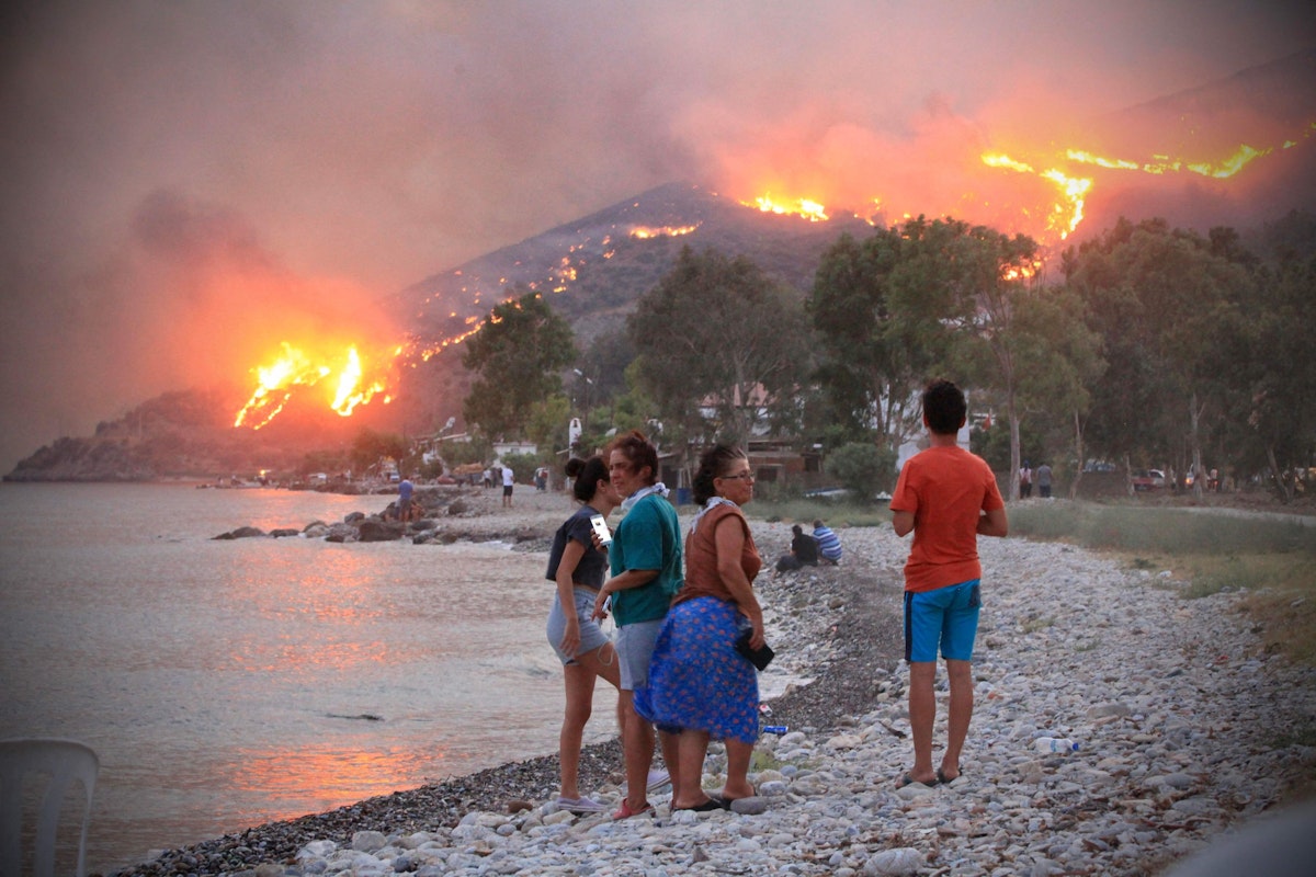 Download von www.picturedesk.com am 13.09.2021 (14:26).  People on a beach watch the blazes spreading up a hill in the Aegean coast city of Oren, near Milas, in the holiday region of Mugla on August 3, 2021 as Turkey struggles against its deadliest wildfires in decades. - The nation of 84 million has been transfixed in horror as the most destructive wildfires in generations erase pristine forests and rich farmland across swaths of Turkey's Mediterranean and Aegean coasts. Tourists have been forced to escape on boats for safety and dozens of villages have been evacuated as wild winds and soaring heat fan the flames. (Photo by STR / AFP) - 20210804_PD9365 - Rechteinfo: Rights Managed (RM) Nur für redaktionelle Nutzung! Werbliche Nutzung erfordert Freigabe: bitte schicken Sie uns eine Anfrage.