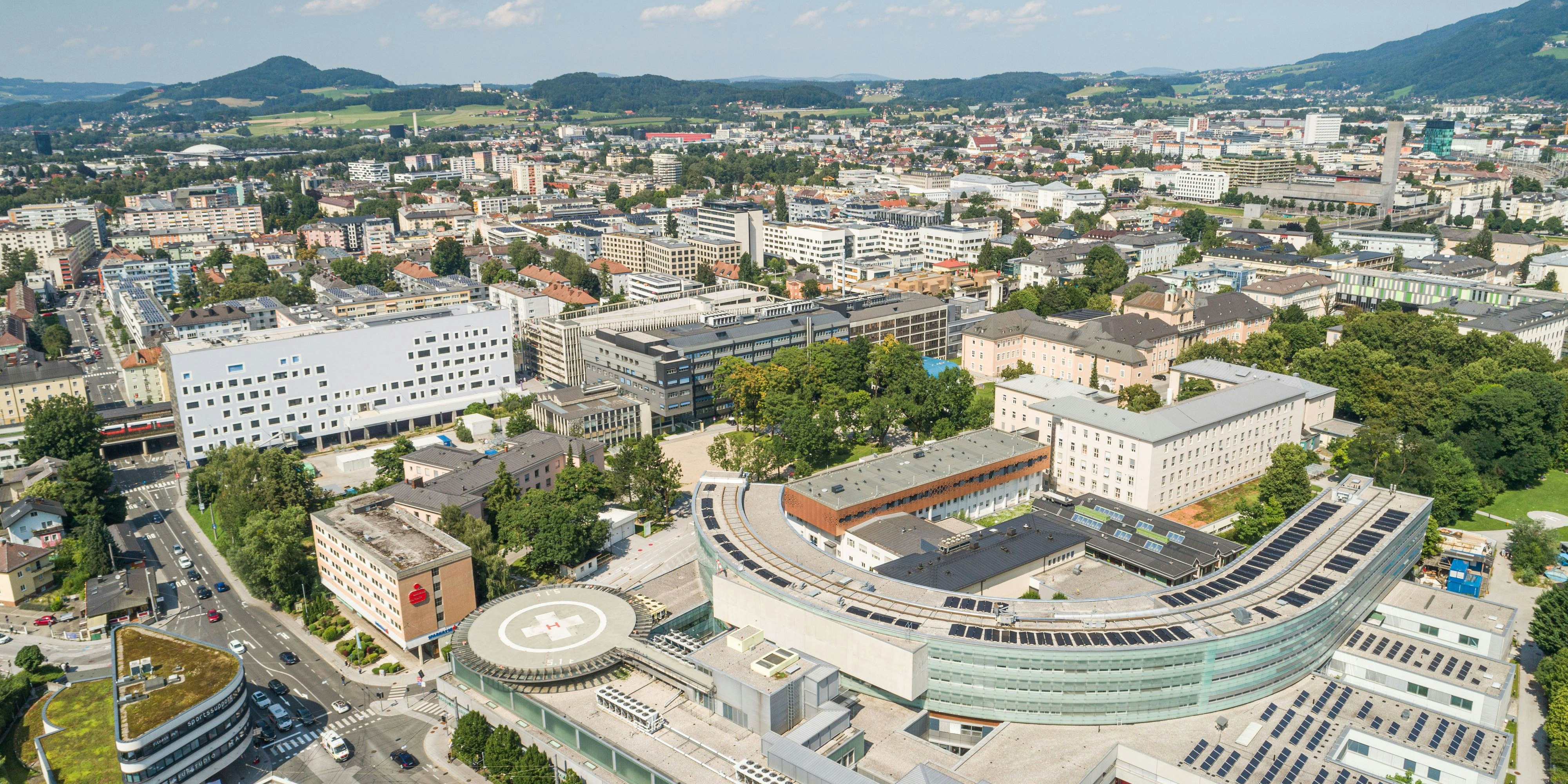 Mittig dunkelgrau im Bild das Parkhaus des LKH Salzburg.