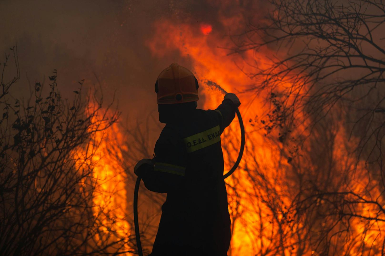Im Sommer 2021 sind infolge einer ungewöhnlich starken Hitzewelle in mehreren Teilen Griechenlands Brände ausgebrochen, auch nahe Athen, wo im Bild ein Feuerwehrmann gegen die Flammen ankämpft.<br>