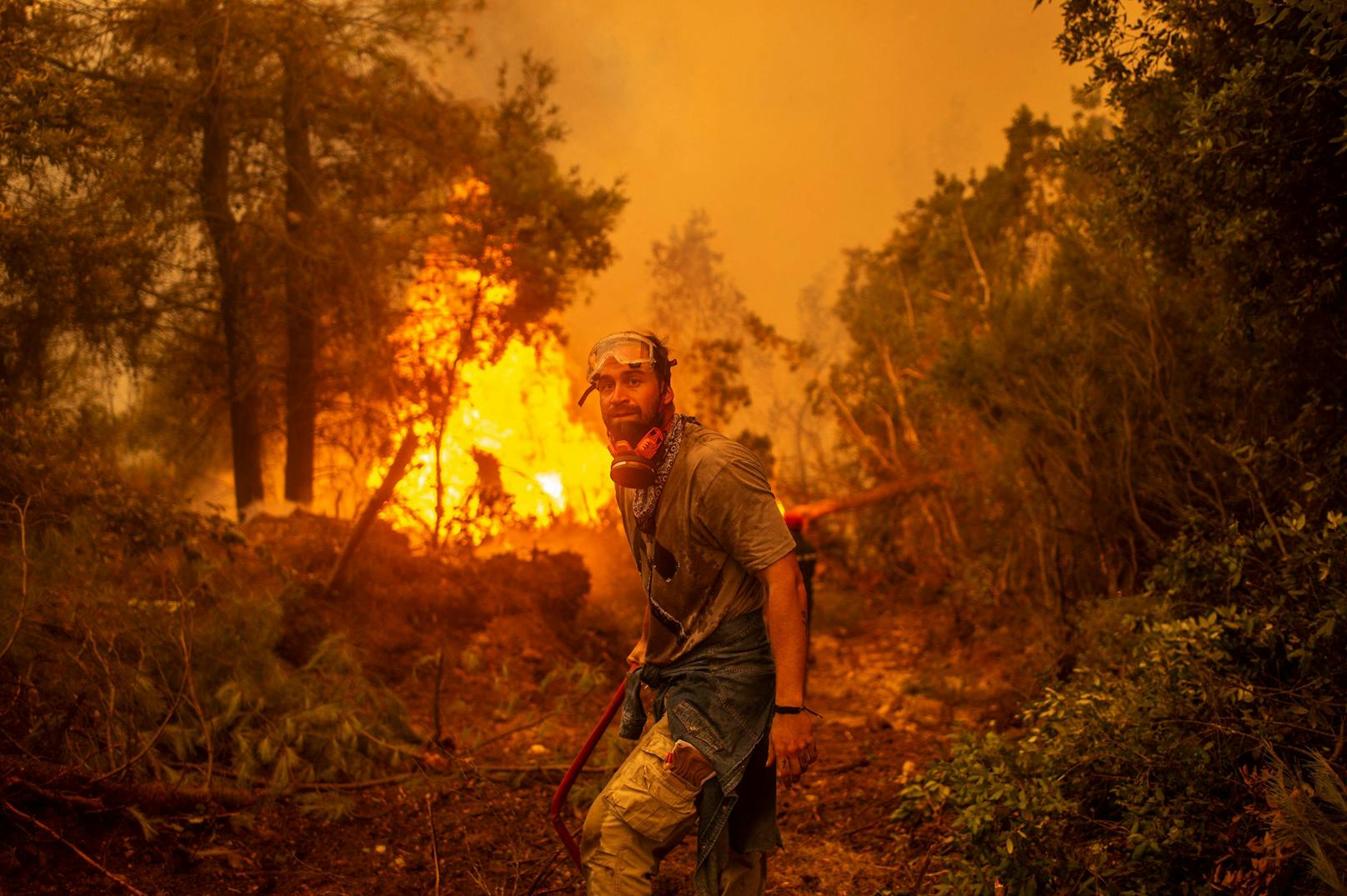 Ein Freiwilliger versucht auf der Insel Euböa ein Feuer zu löschen. Die ungewöhnliche Hitzewelle in Griechenland wird mit der globalen Klimakrise in Verbindung gebracht.<br>