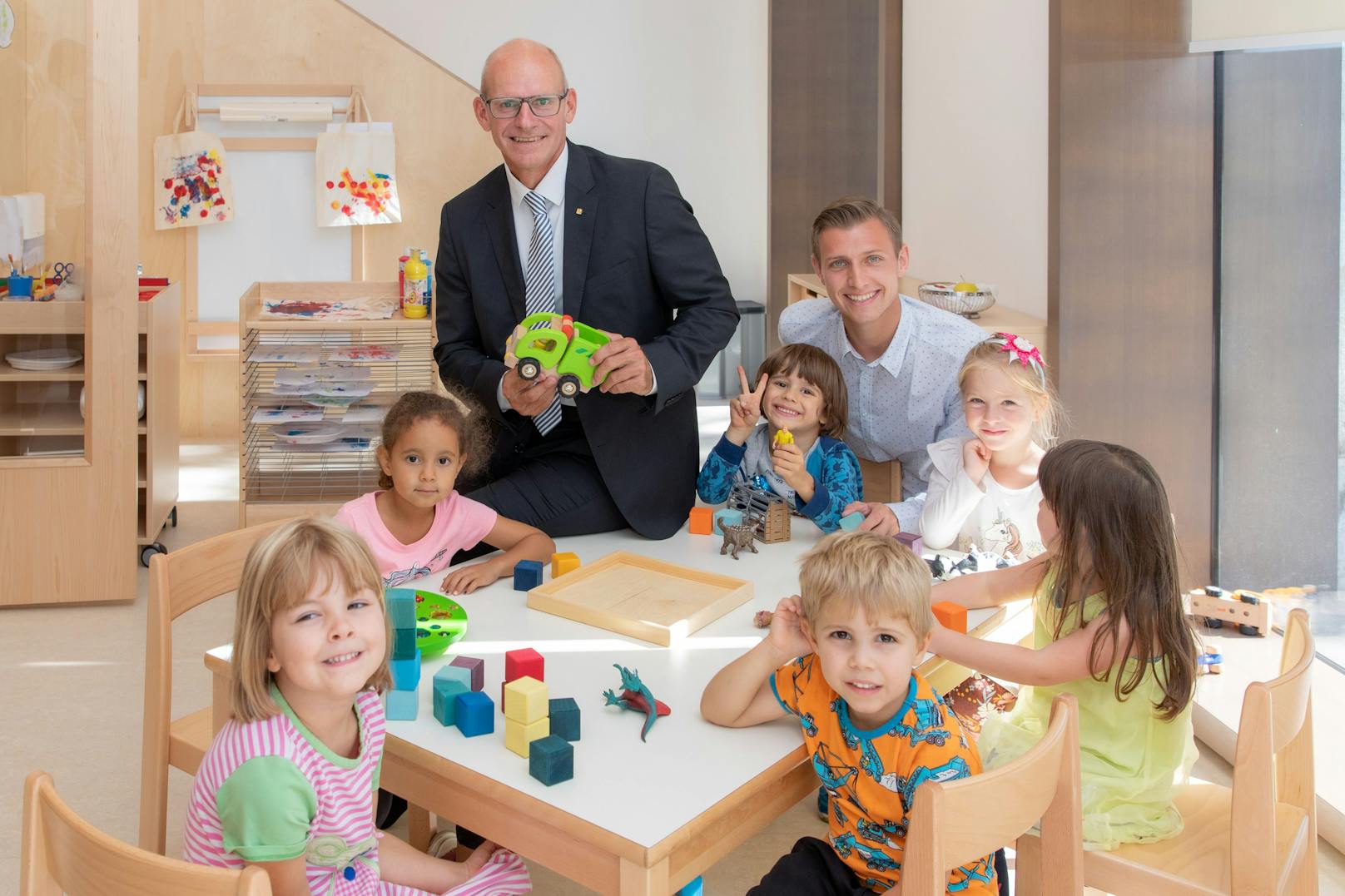 Generaldirektor Dr. Ralph Müller (Mitte) und Kindergartenleiter Oskar Huber mit Kindern im neuen Kindergarten der Wiener Städtischen Versicherung.