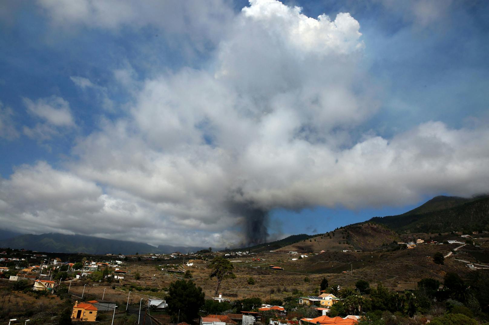 Der Berg Cumbre Vieja bricht aus und spuckt eine Säule aus Rauch, Asche und Lava aus, wie man von Los Llanos de Aridane auf der Kanareninsel La Palma am 19. September 2021 sieht.<br>