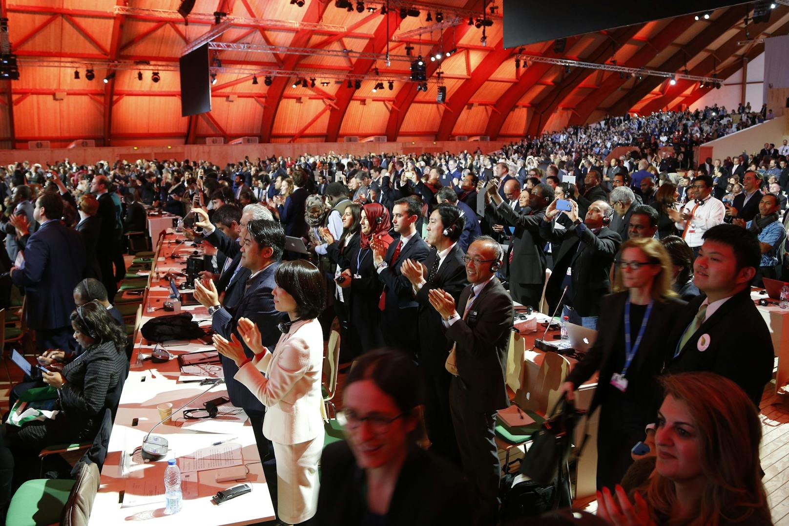 Delegierte jubeln am 12. Dezember 2015 nach der Verabschiedung eines historischen Pakts zur Eindämmung der globalen Erderhitzung auf der COP21-Klimakonferenz in Paris.<br>