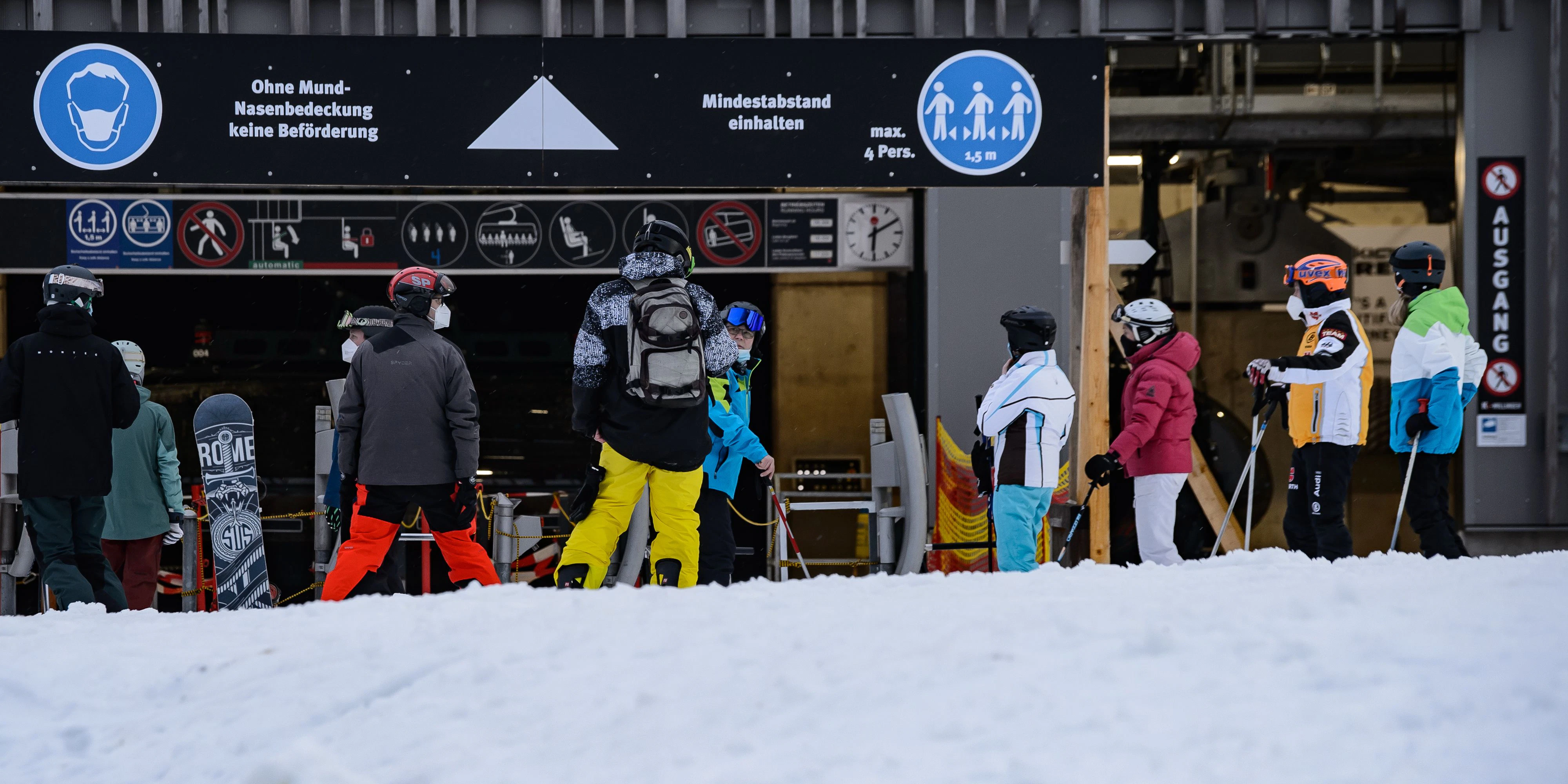 Download von www.picturedesk.com am 21.09.2021 (09:41).  09 March 2021, Hessen, Willingen: Winter sports enthusiasts stand in front of a sign "No transport without mouth-nose covering" and "Keep minimum distance" while floodlight skiing at the valley station. The ski slope at Kaltenhagen in the Sauerland region of northern Hesse has been open to winter sports enthusiasts since 08.03.2021. Photo: Swen Pförtner/dpa - 20210309_PD8244 - Rechteinfo: Rights Managed (RM)