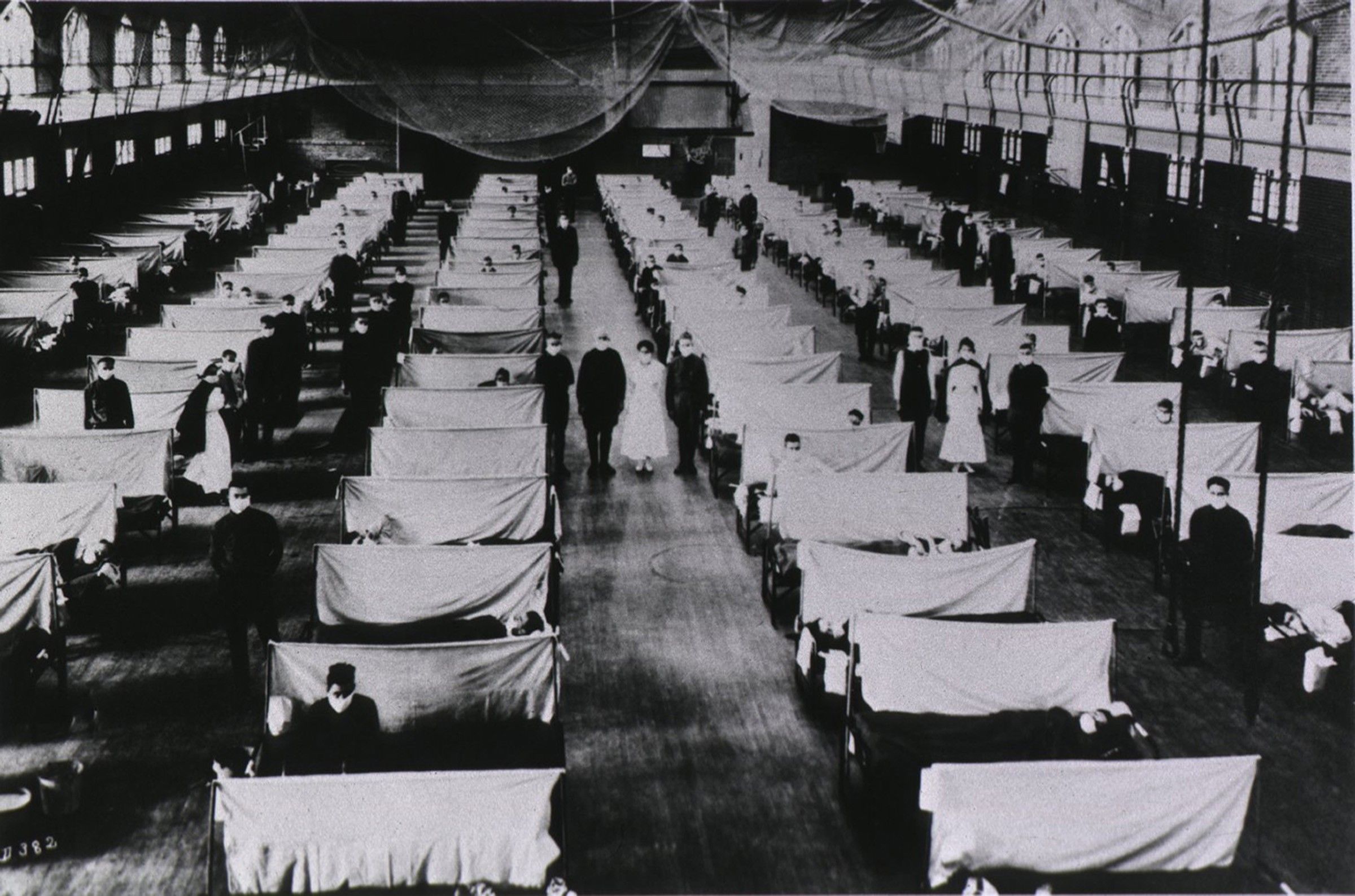 Download von www.picturedesk.com am 22.09.2021 (11:38).  Spanish Flu Epidemic 1918-19. U.S. school gymnasium converted into an flu ward with patients' beds are separated by screens and masked health workers. An estimated 25% of the US population contracted the flu and over 500,000 died. - 20110817_PD1836 - Rechteinfo: Rights Managed (RM)