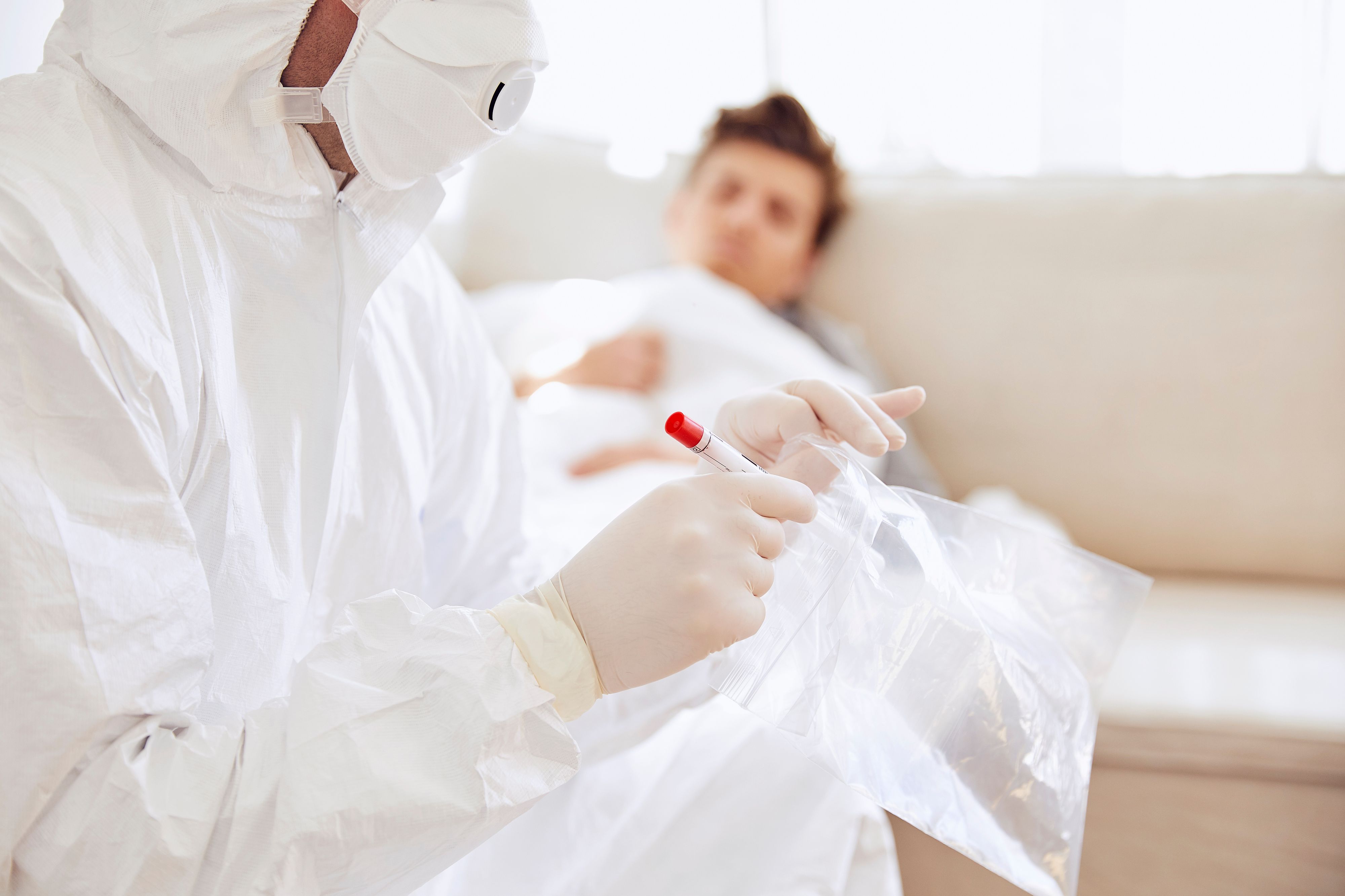 Download von www.picturedesk.com am 22.09.2021 (14:11).  Close-up of doctor holding medical sample in plastic bag while patient resting on sofa - 20200810_PD10815 - Rechteinfo: Royalty Free (RF) Model Released