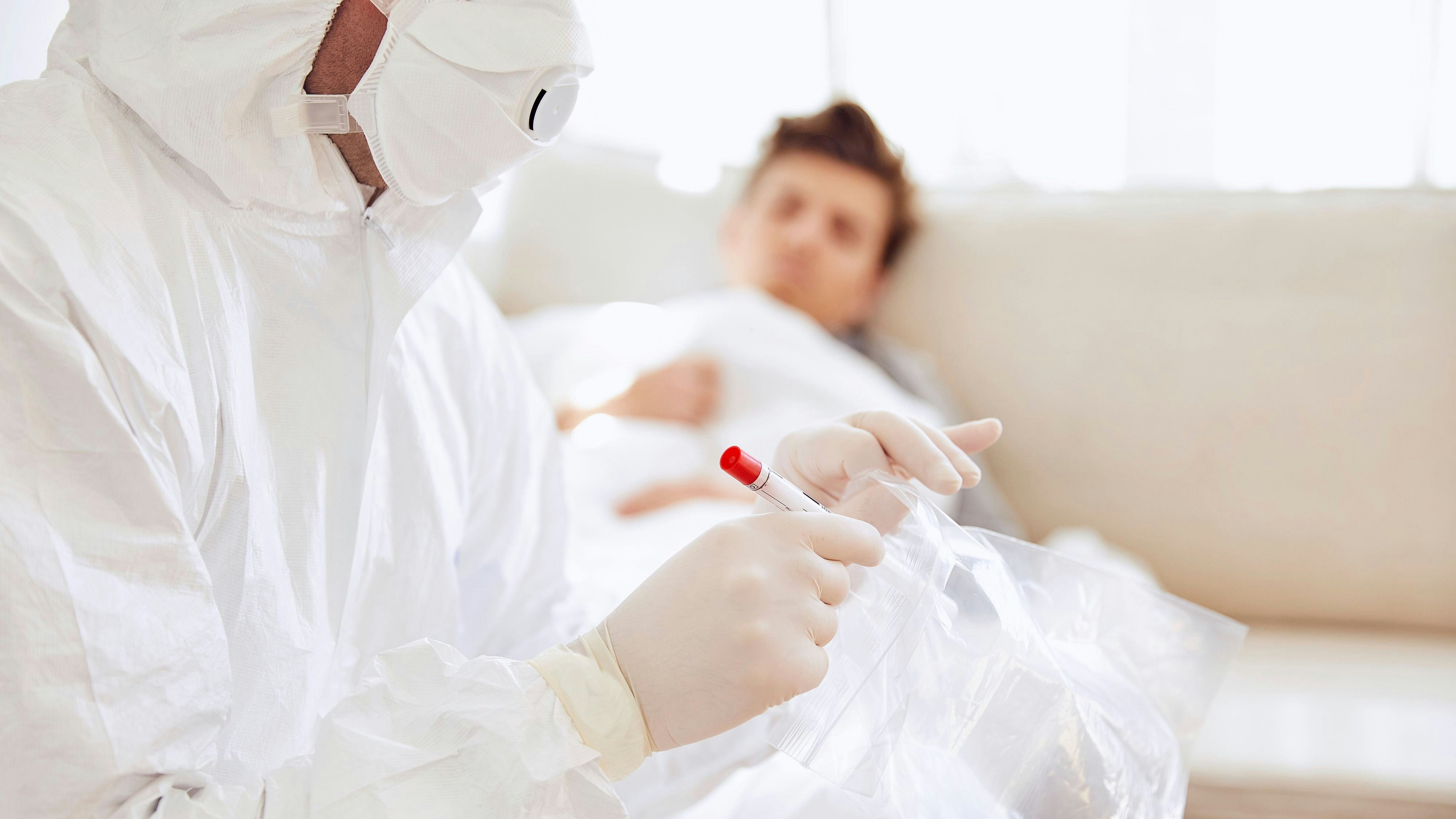 Download von www.picturedesk.com am 22.09.2021 (14:11).  Close-up of doctor holding medical sample in plastic bag while patient resting on sofa - 20200810_PD10815 - Rechteinfo: Royalty Free (RF) Model Released