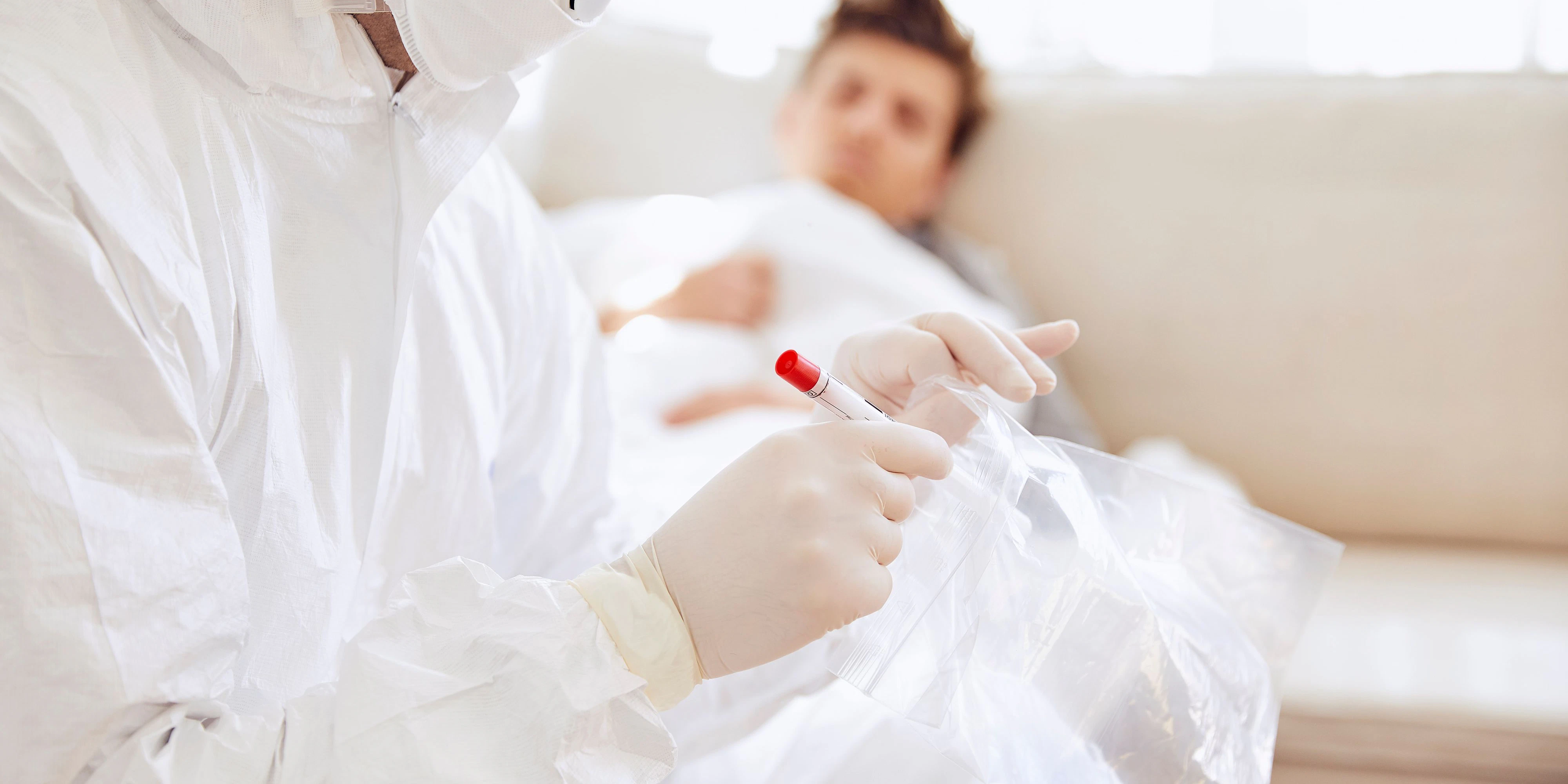 Download von www.picturedesk.com am 22.09.2021 (14:11).  Close-up of doctor holding medical sample in plastic bag while patient resting on sofa - 20200810_PD10815 - Rechteinfo: Royalty Free (RF) Model Released