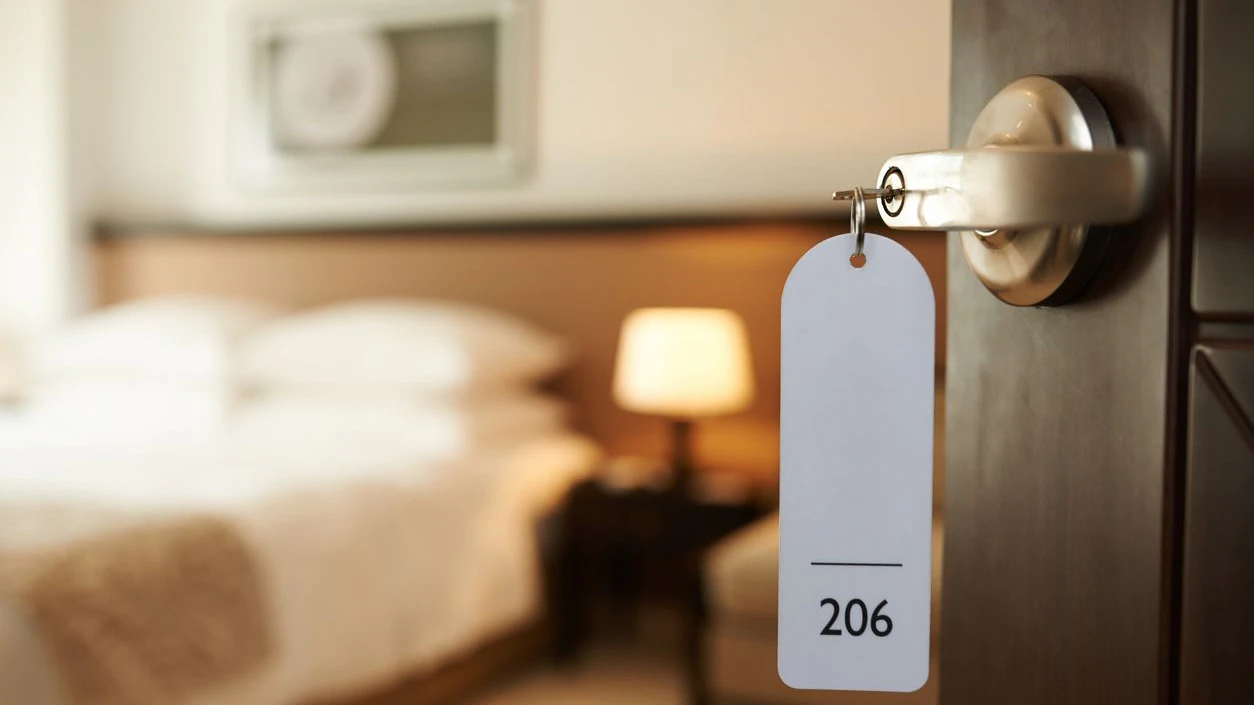 Opened door of hotel room with key in the lock