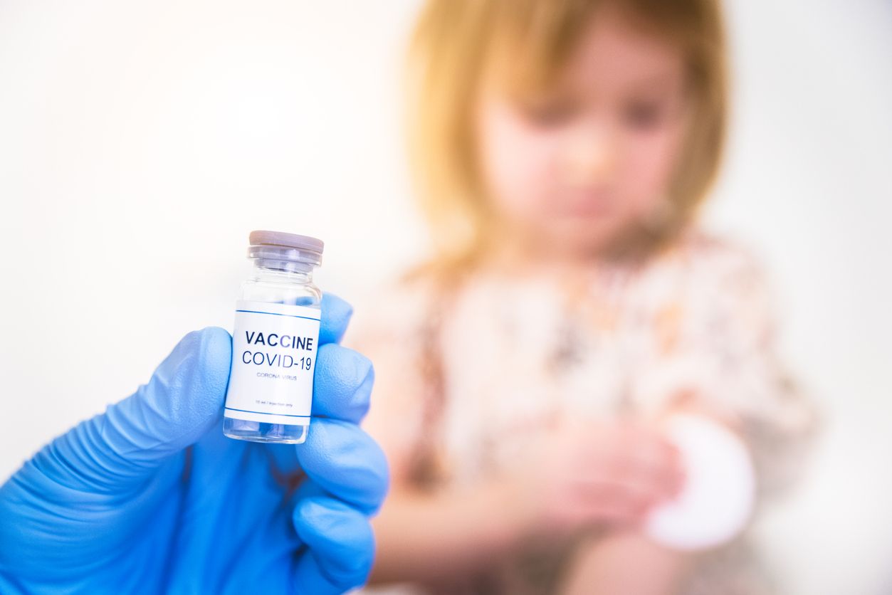 Girl to be vaccinated against COVID-19 with coronavirus vaccine drawn into an injection needle by healthcare worker, nurse or doctor wearing blue protective gloves.