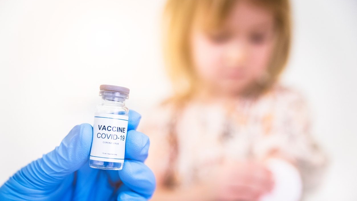 Girl to be vaccinated against COVID-19 with coronavirus vaccine drawn into an injection needle by healthcare worker, nurse or doctor wearing blue protective gloves.