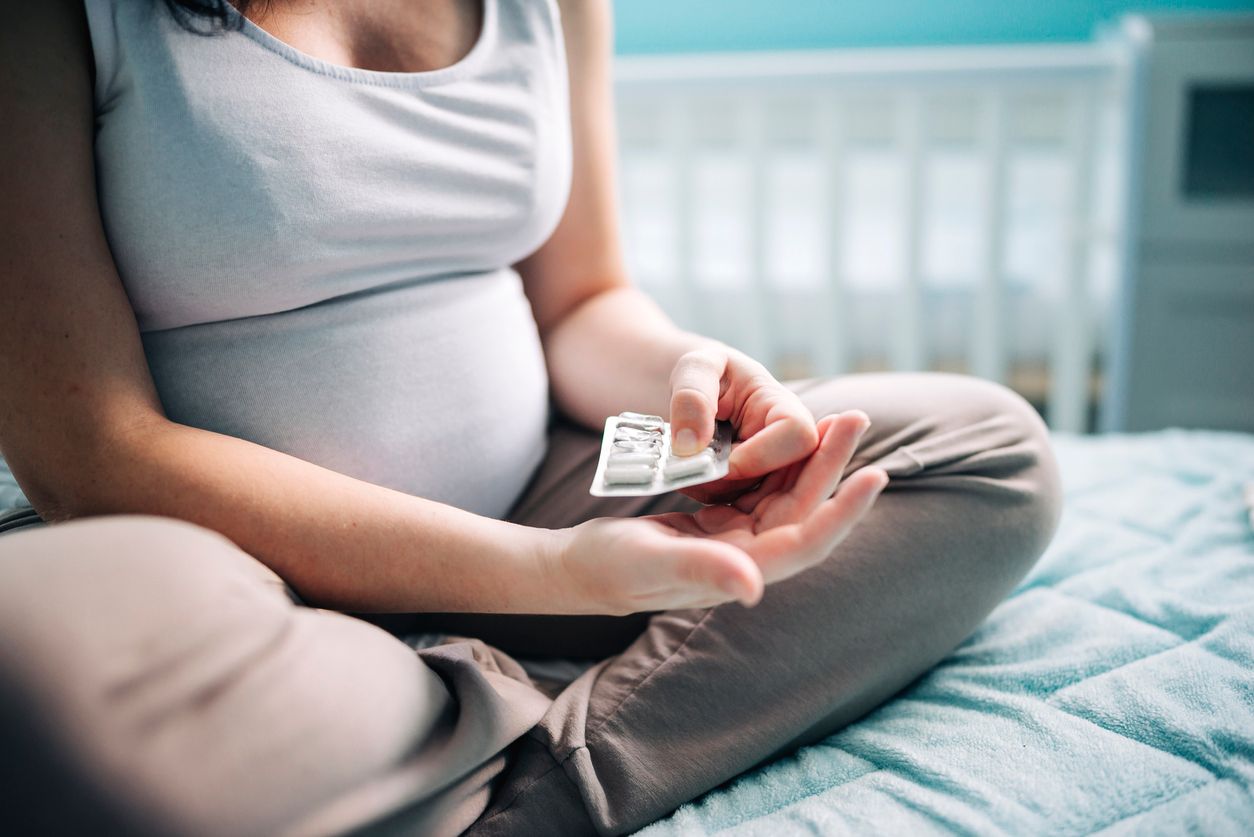 Young pregnant woman holding pills in hand