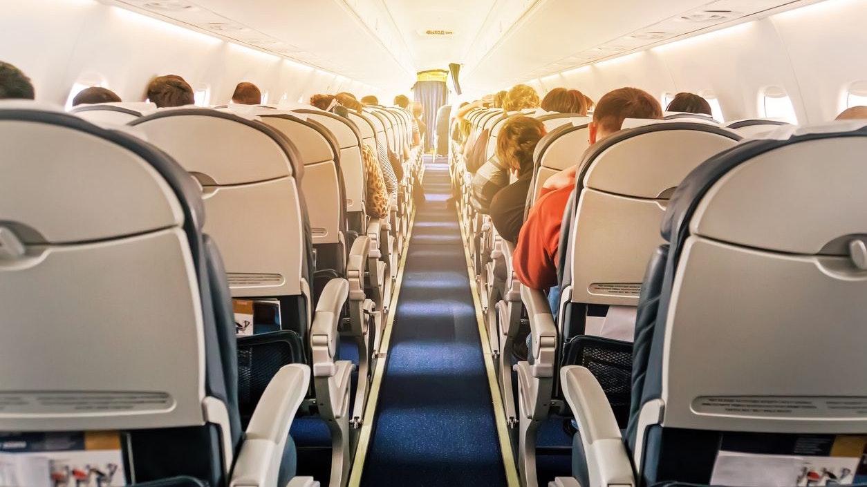 Commercial aircraft cabin with rows of seats down the aisle. morning light in the salon of the airliner. economy class