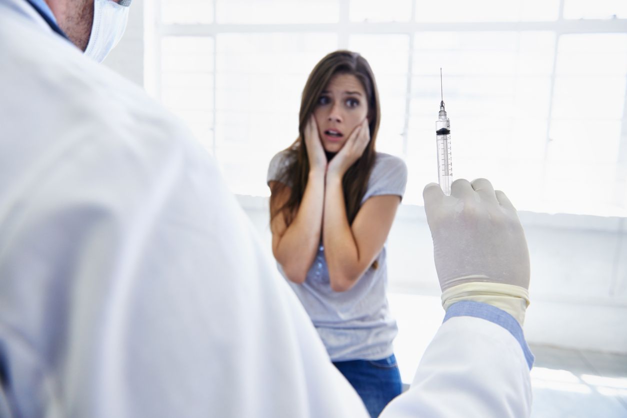 A doctor preparing to give a nervous young woman an injection
