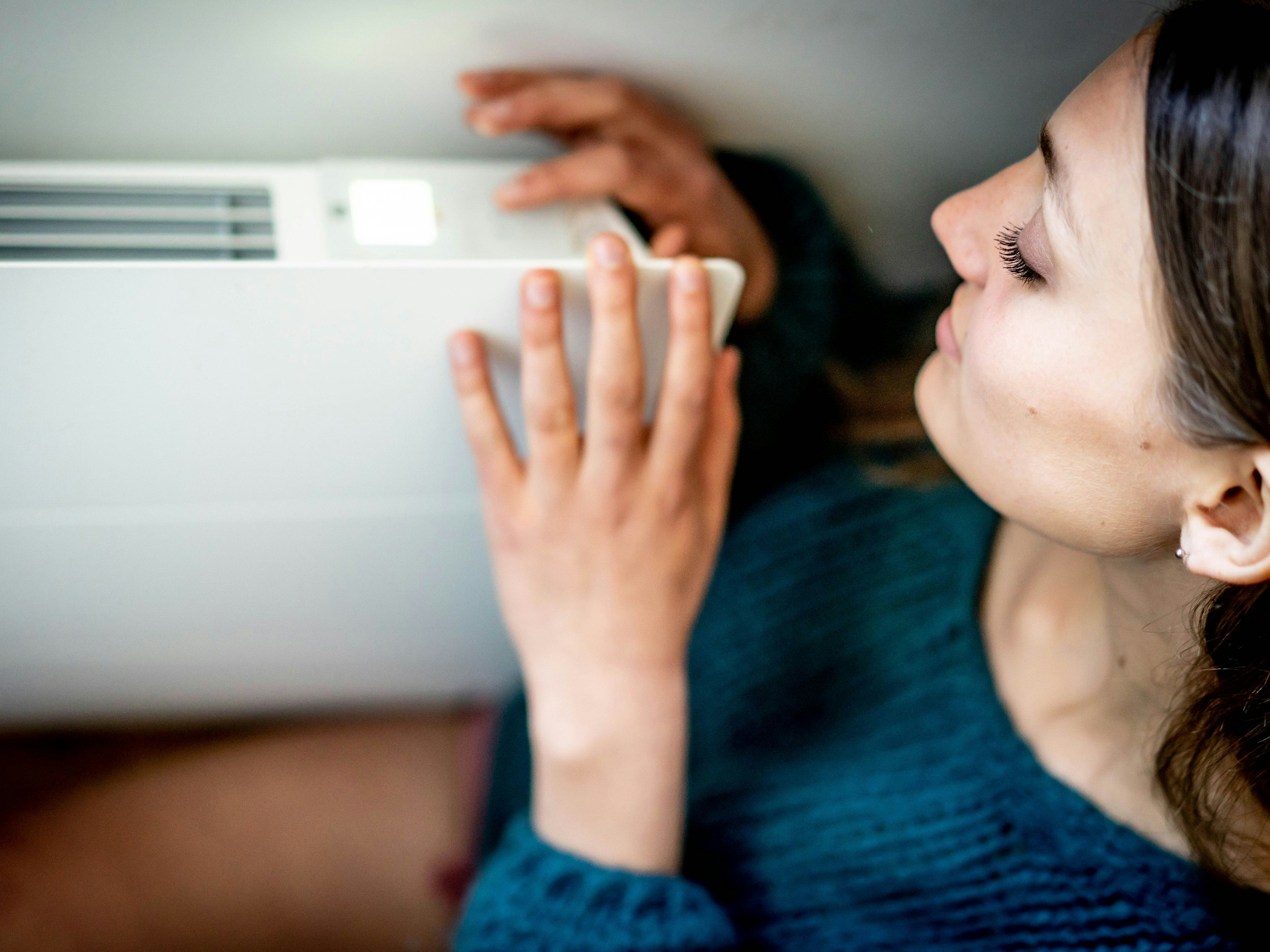 Download von www.picturedesk.com am 30.09.2021 (16:48).  Woman adjusting a thermostatic radiator valve on a domestic radiator. - 20210415_PD15243 - Rechteinfo: Rights Managed (RM) Model Released