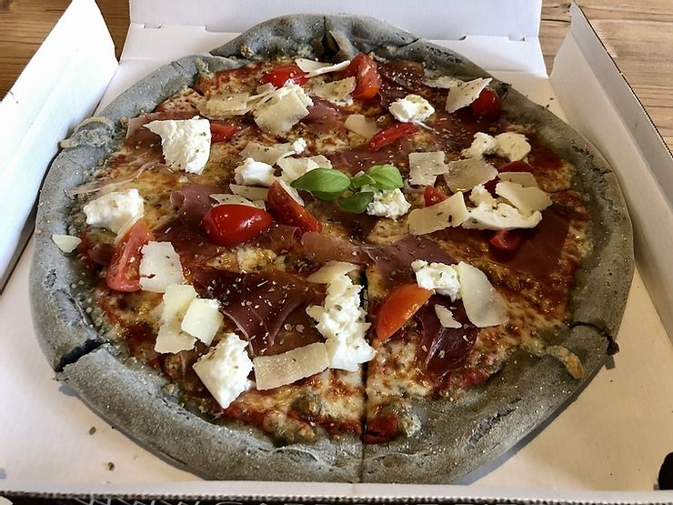 Die Kruste täuscht, die Pizza ist nicht verbrannt. Der Teig wurde mit Aktivkohle schwarz eingefärbt.