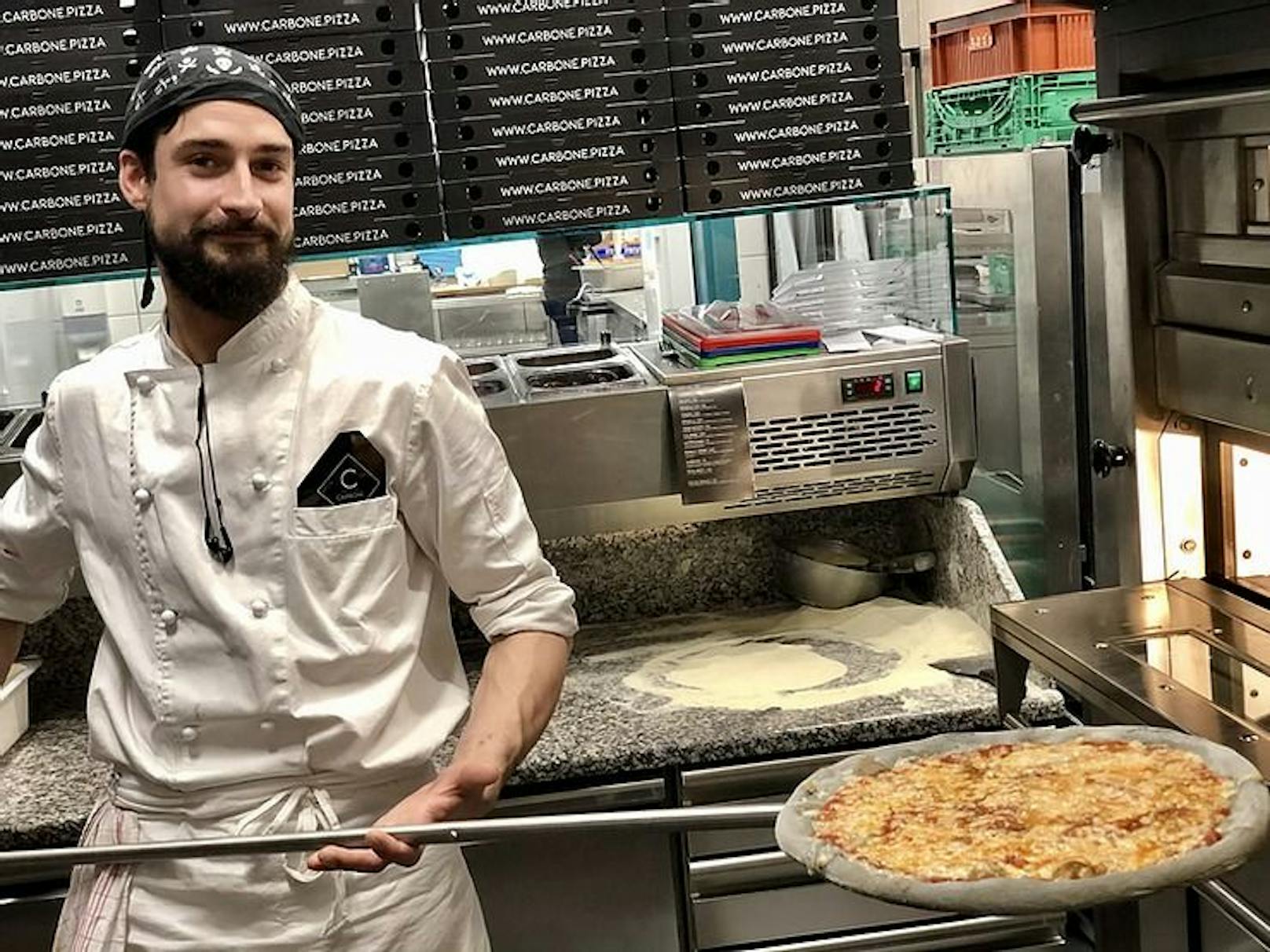 Pizzabäcker Cristian schiebt die Black-Pizza in den Steinbackofen.