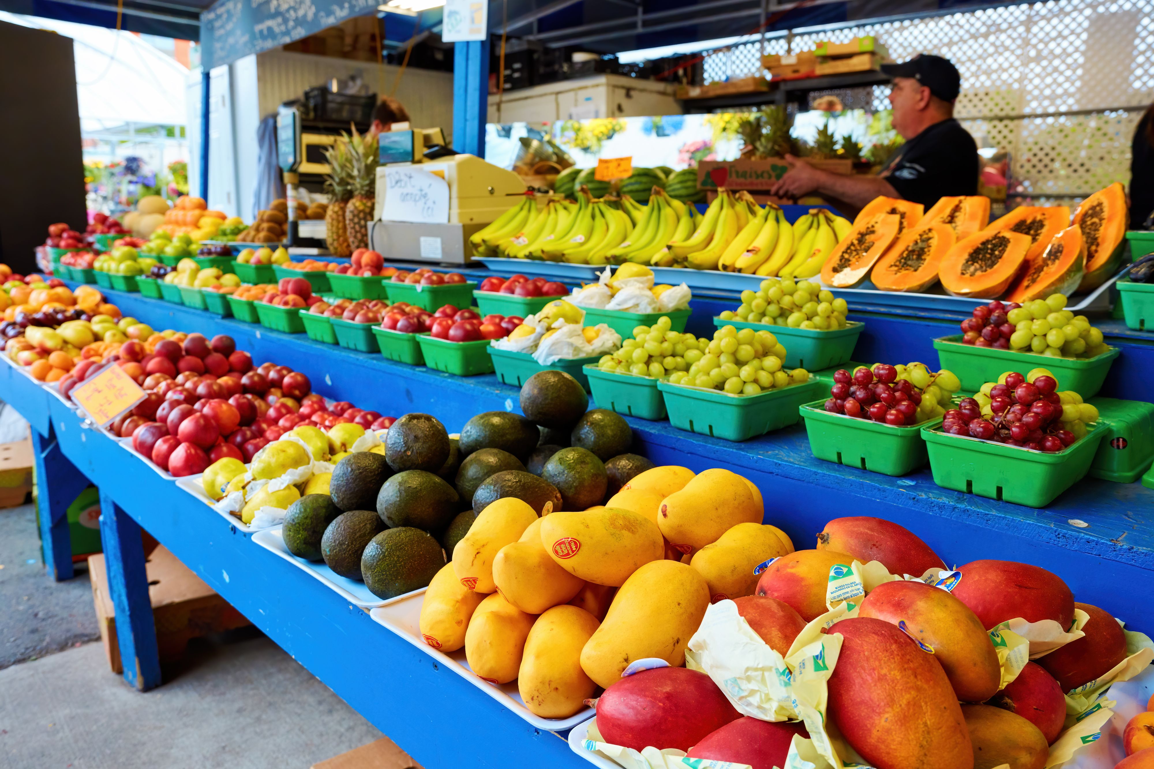 Montreal, Canada, June, 2018: Various fruits on the stall with a salesman behind the counter at Atwater market in Montreal, Quebec, Canada.