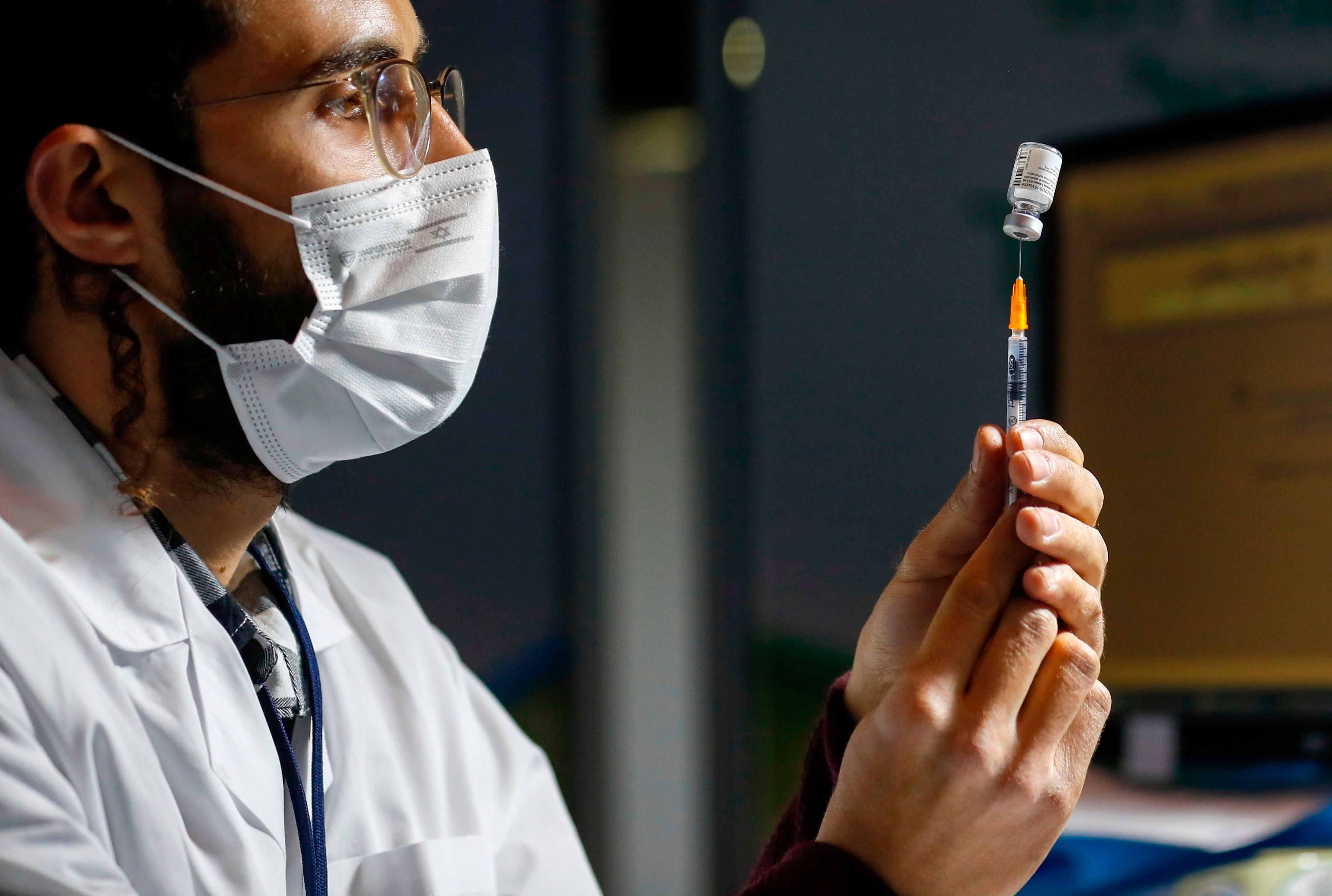 An Israeli healthcare worker prepares a dose of the COVID-19 vaccine for people queuing at the Kupat Holim Clalit clinic in Jerusalem, on January 14, 2021. - Israel's initial vaccination rollout appears to be unfolding successfully, with some two million citizens having received the first of two required injections of the Pfizer-BioNTech jab, a pace widely described as the world's fastest per capita. (Photo by AHMAD GHARABLI / AFP) - 20210114_PD5707 - Rechteinfo: Rights Managed (RM) Nur für redaktionelle Nutzung! Werbliche Nutzung erfordert Freigabe: bitte schicken Sie uns eine Anfrage.