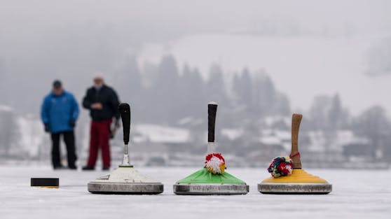 Ausflügler beim Eisstock schießen auf einem zugefrorenen See. Symbolbild