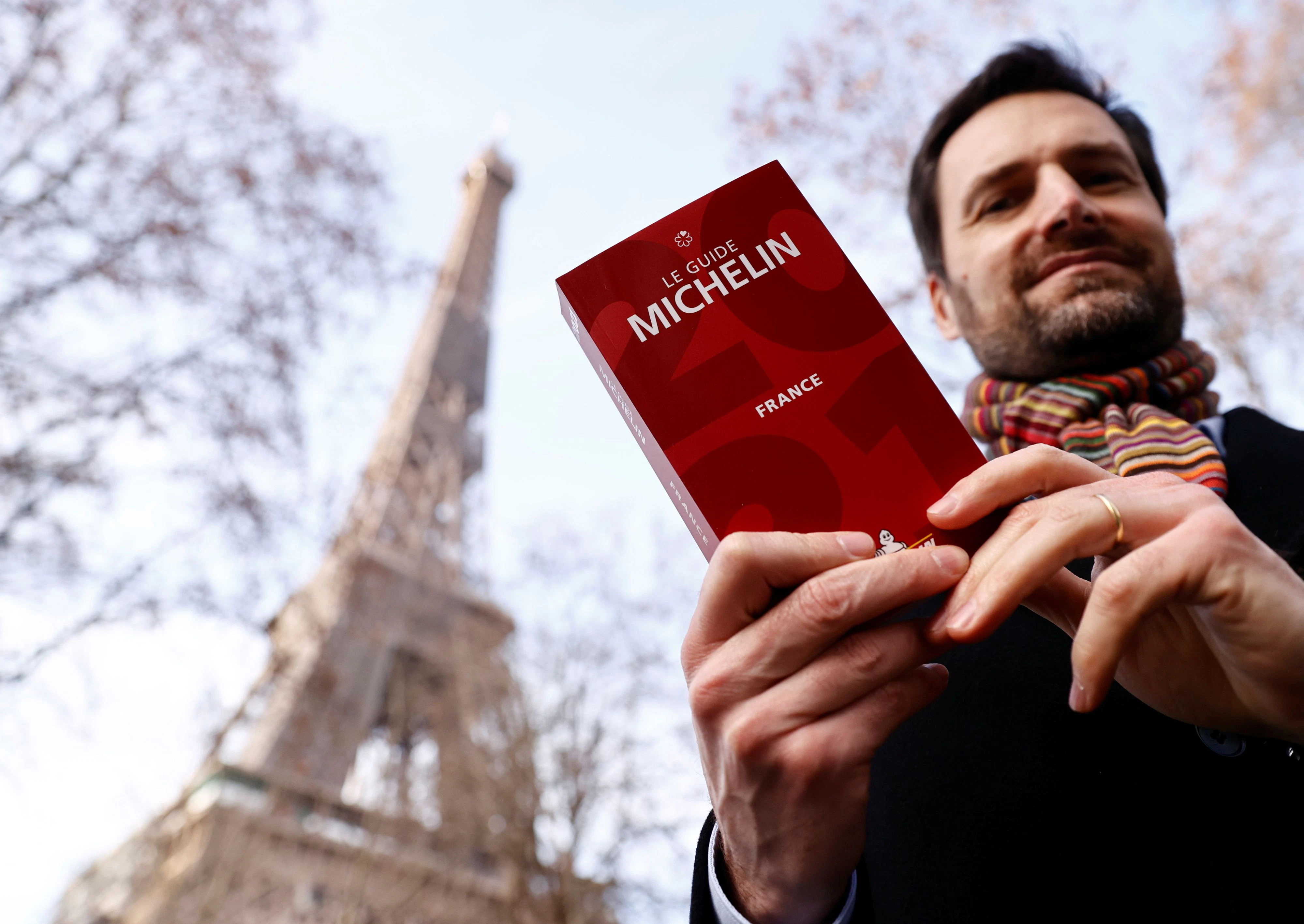Gwendal Poullennec, International Director of Michelin Guides poses holding a copy of the Michelin Guide 2021 before the ceremony to award stars to French restaurants, which have been closed for months due to restrictions against the spread of the coronavirus disease (COVID-19), in Paris, France, January 18, 2021.    REUTERS/Christian Hartmann