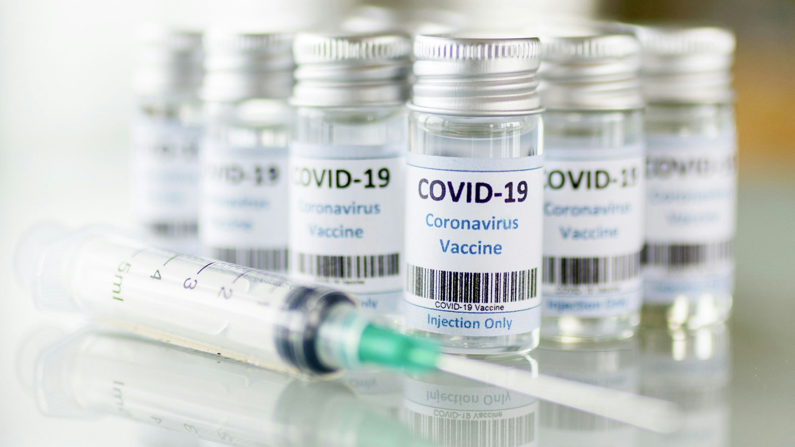 Impfdosen und Impfspritzen stehen auf einem Tisch. Symbolbild