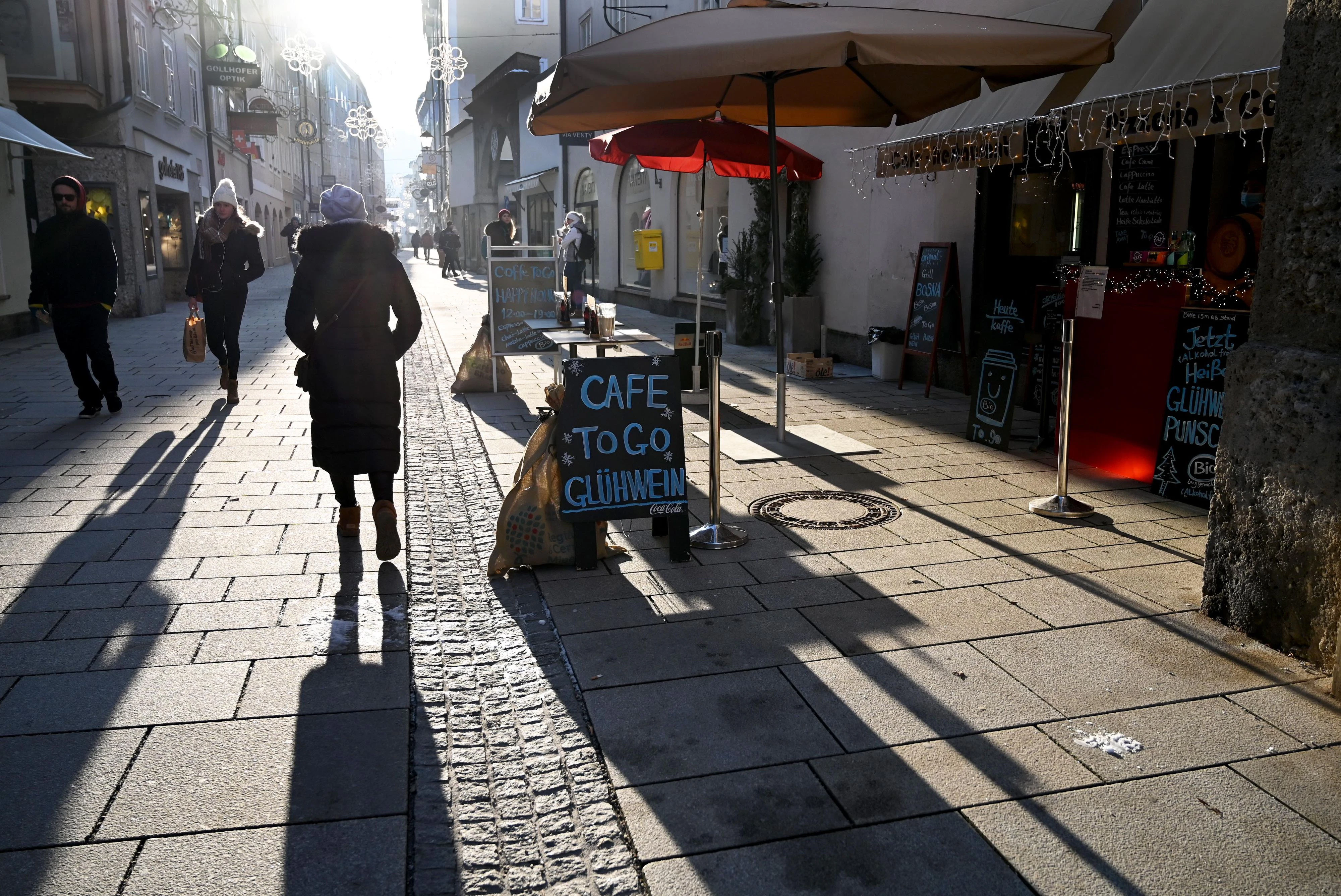 Passanten gehen im Gegenlicht in einer Salzburger Einkaufsstraße. Symbolbild