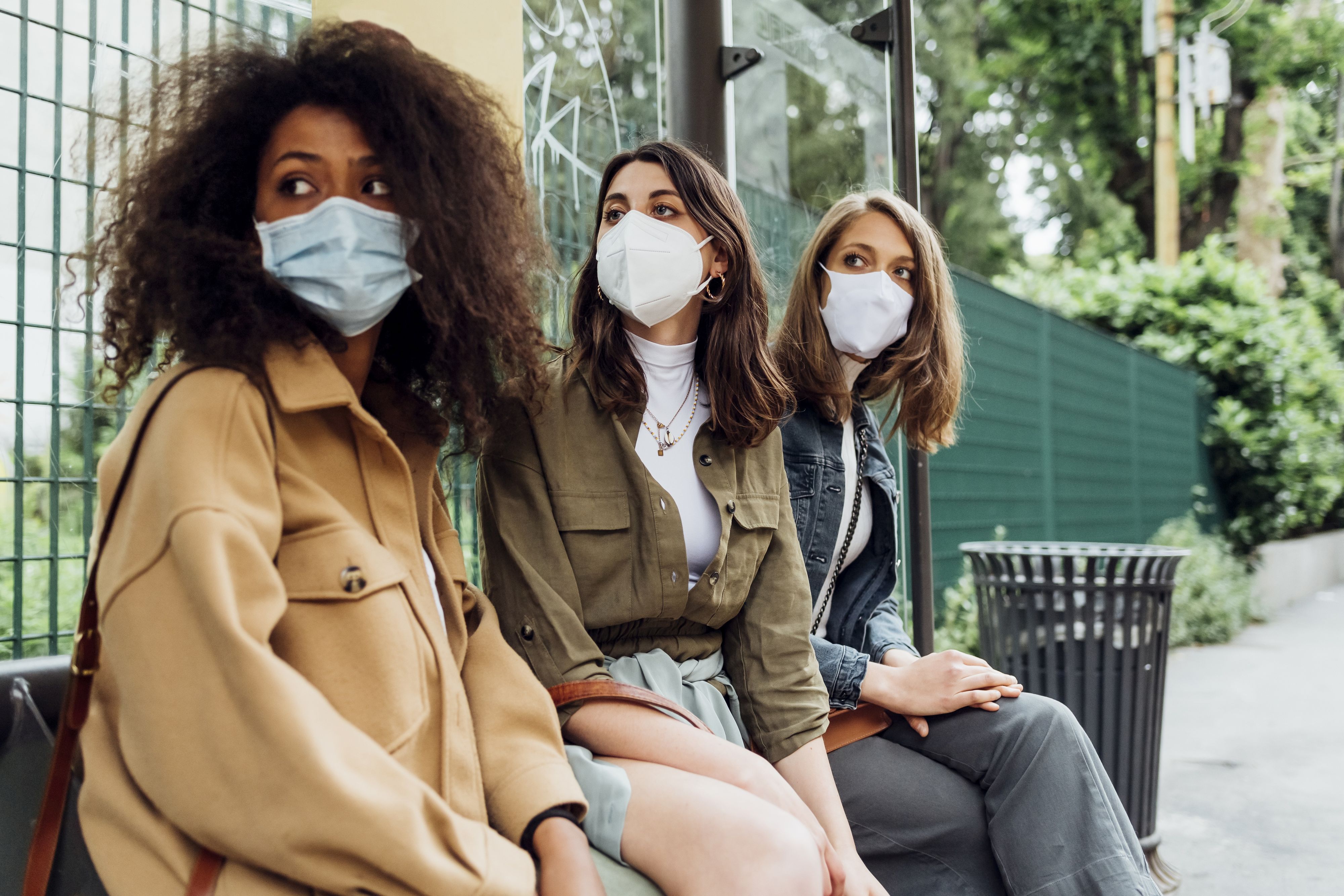 Download von www.picturedesk.com am 01.10.2021 (10:07).  Young women with protective face mask sitting at bus stop - 20210715_PD19939 - Rechteinfo: Royalty Free (RF) Model Released