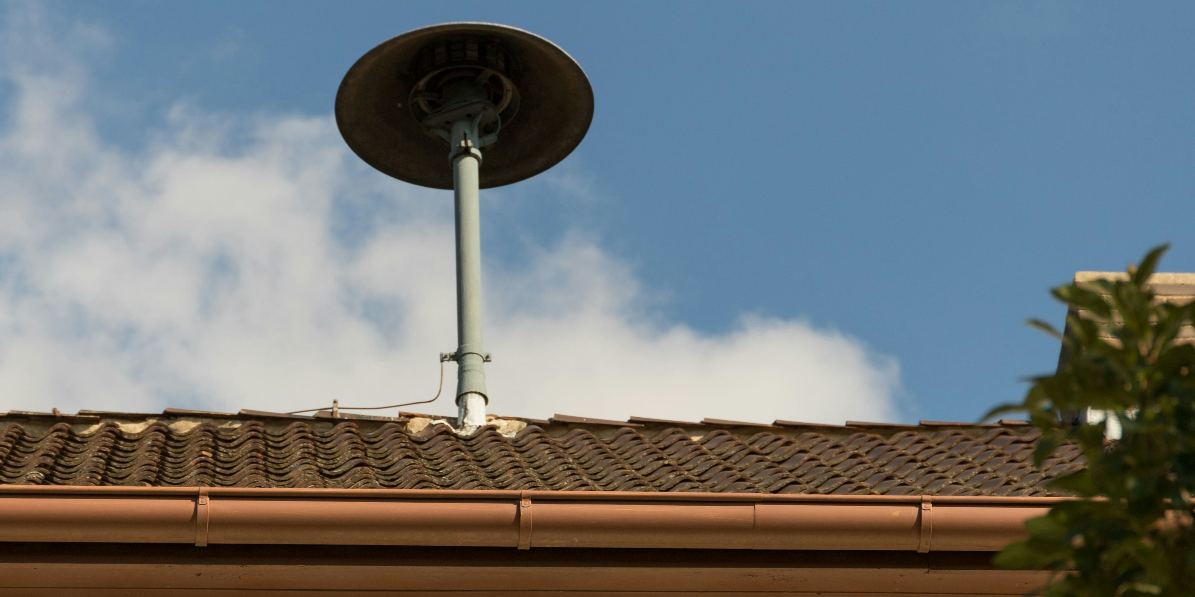Fire siren on a roof in a village with blue sky