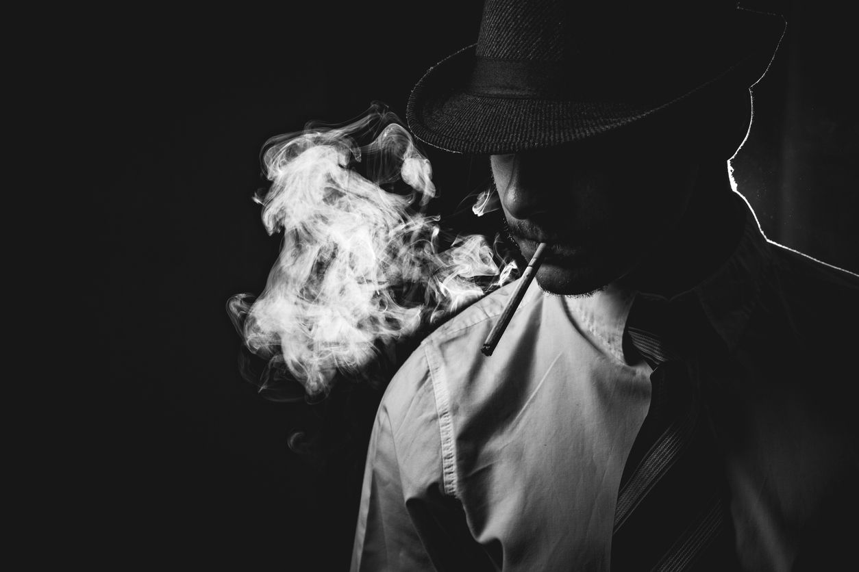 Retro man in smoke with hat, shirt and tie, smoking cigarette, black and white. Noir style.