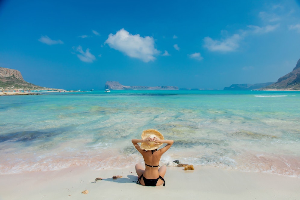 Young redhead girl in black bikini and with hat on Balos beach, west Crete, Greece. Summertime season vacation, July