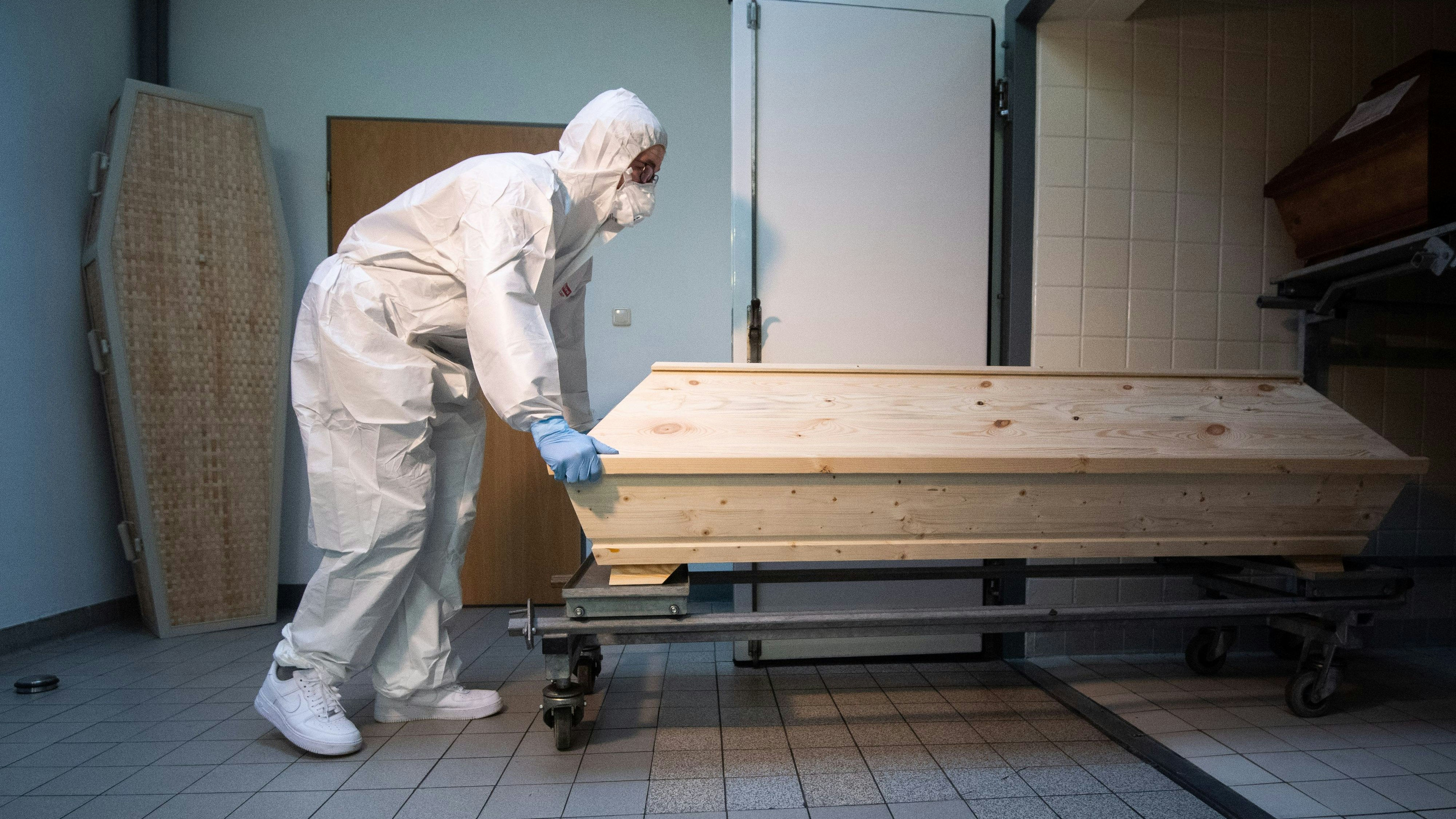 Download von www.picturedesk.com am 13.10.2021 (12:38).  13 January 2021, Lower Saxony, Celle: Employee Niklas Grube pushes a coffin into a cooling chamber at the crematorium "Die Feuerbestattungen Celle", which contains coffins of deceased persons who died with or from the Corona virus. The crematorium in Celle has recorded an increase in cremations of Corona dead since November 2020. Photo: Julian Stratenschulte/dpa - 20210113_PD1992 - Rechteinfo: Rights Managed (RM)