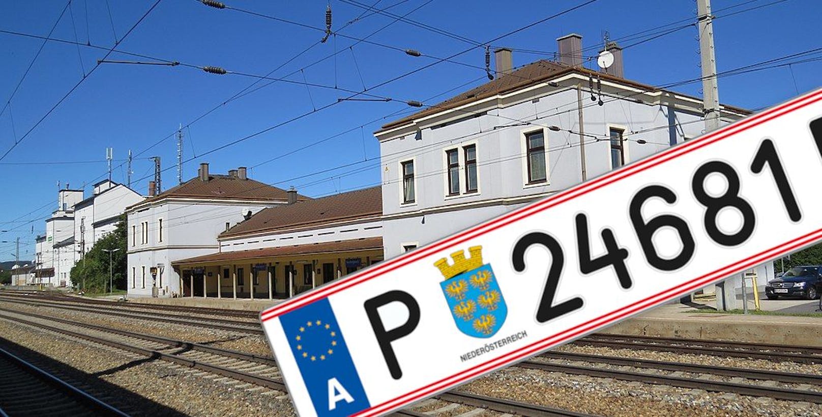 Symbolfoto eines Autokennzeichens und der Bahnhof Neulengbach im Hintergrund.