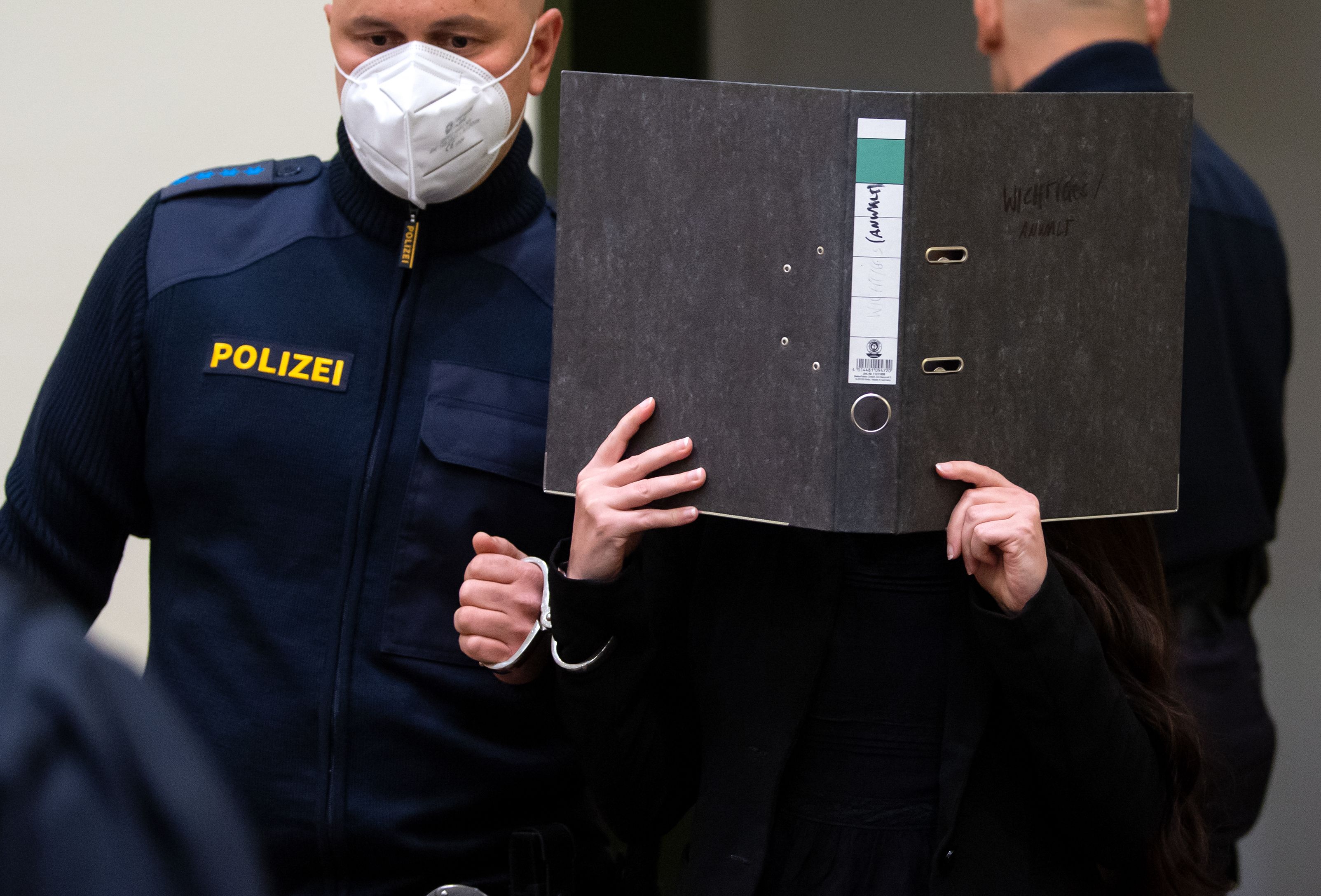 Download von www.picturedesk.com am 25.10.2021 (11:21).  25 October 2021, Bavaria, Munich: The defendant Jennifer W. (M) is led into the courtroom before the trial begins. The woman from Lohne in Lower Saxony is charged with murder and war crimes. As an IS supporter in Iraq, she is said to have stood idly by while a small Yazidi girl was chained in a courtyard and died of thirst. Photo: Sven Hoppe/dpa - 20211025_PD1003 - Rechteinfo: Rights Managed (RM)