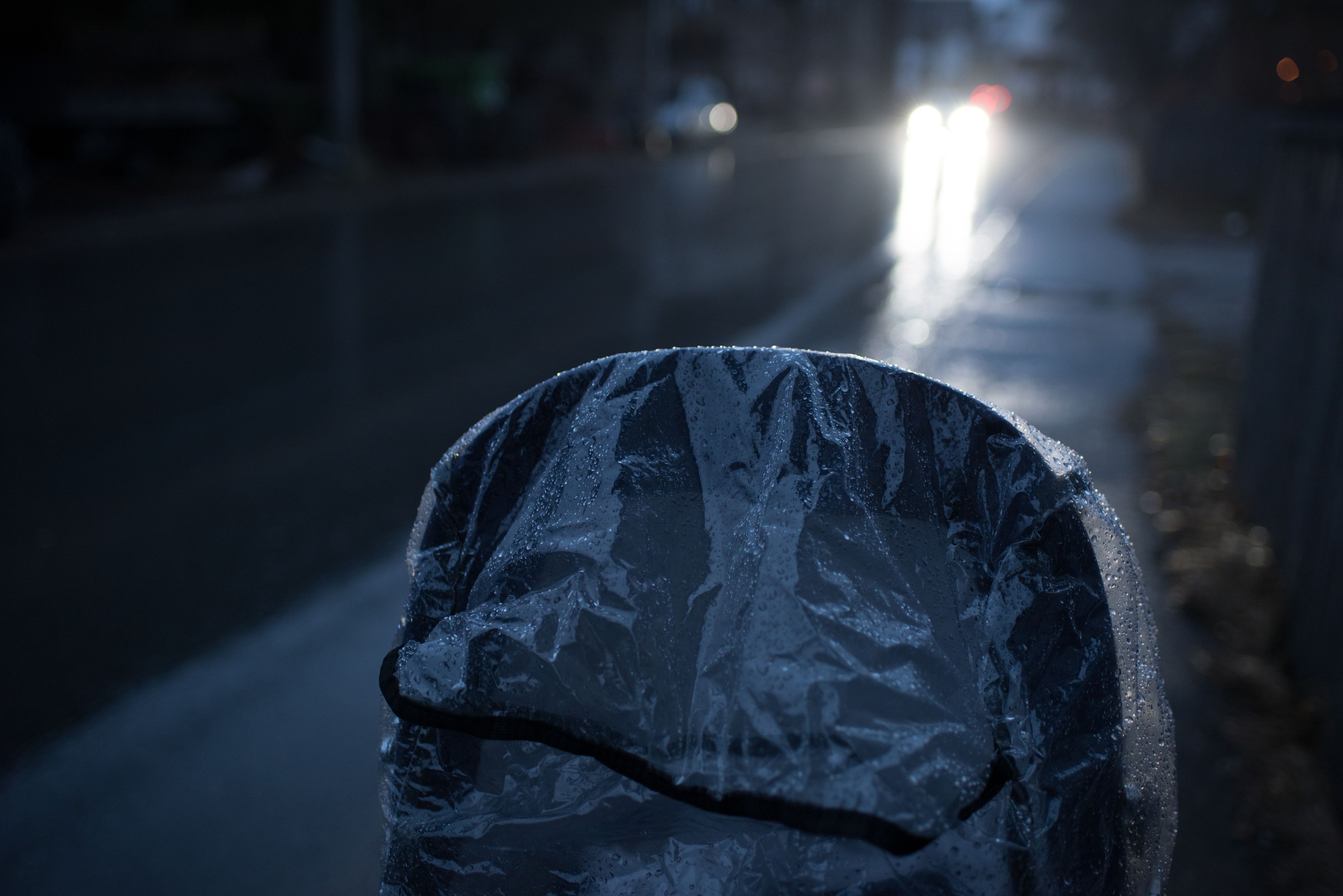 rain protection on stroller, detail of stroller, red and white lights of cars