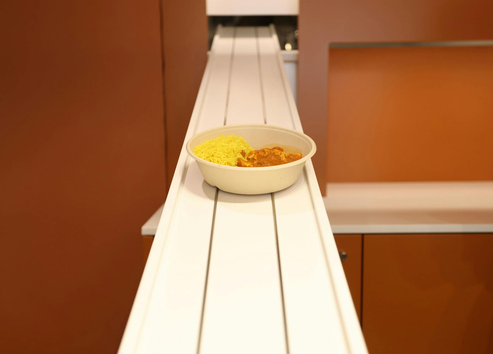 Das klassische&nbsp;Cicken Curry zum Mitnehmen kommt über eine Rutsche zur Theke, wo es sein Finish bekommt.