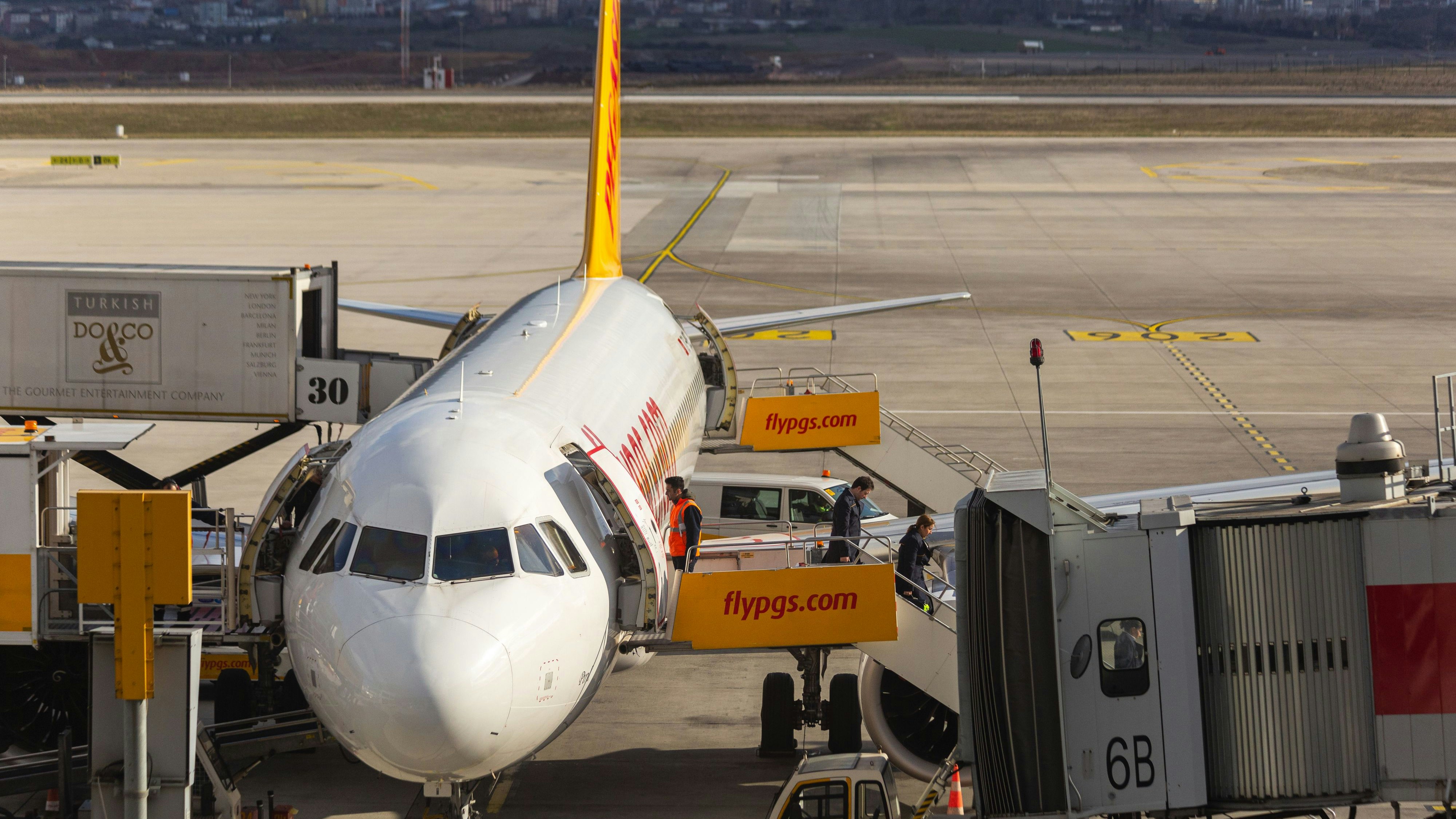Sabiha Gokcen, Istanbul, Turkey - February 16 2020: Airbus A320 type airliner parked in service area with ambulift, catering lift and air jetty conntected. Cabin crew and flight personnel get off from the plane. Front view.