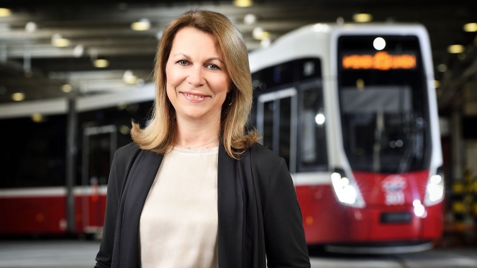 Alexandra Reinagl, Geschäftsführerin für Personal, Finanzen und Recht, vor einer Straßenbahn des Typs Flexity.