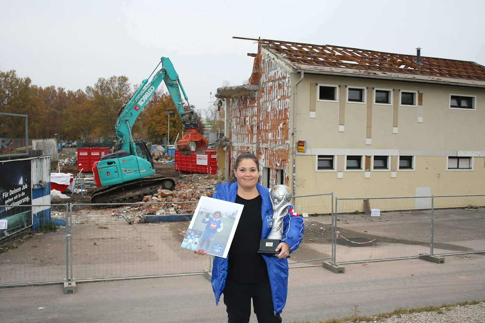 Gudrun Radler zeigt den Aufstiegspokal und ein Foto eines Ex-Blau-Weiß-Kickers.