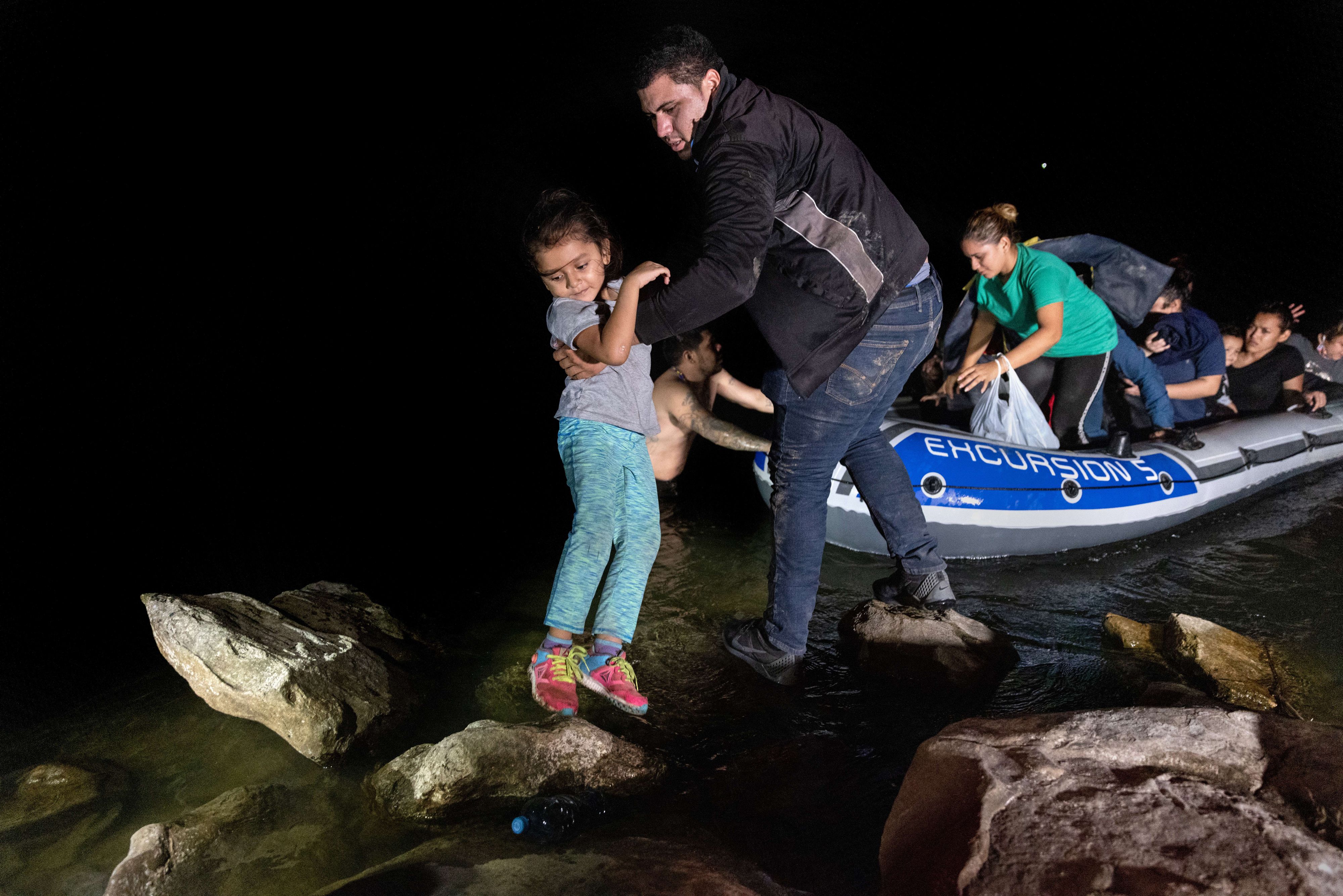 Download von www.picturedesk.com am 12.11.2021 (12:05).  ROMA, TEXAS - APRIL 14: An immigrant lifts a child from a dinghy onto the bank of the Rio Grande after being smuggled across the U.S.-Mexico border on April 14, 2021 in Roma, Texas. A surge of mostly Central American immigrants crossing into the United States, including record numbers of children, has challenged U.S. immigration agencies along the U.S. southern border. John Moore/Getty Images/AFP.== FOR NEWSPAPERS, INTERNET, TELCOS & TELEVISION USE ONLY == - 20210414_PD11893 - Rechteinfo: Rights Managed (RM) Fotografische Urheberrechte sind garantiert. Der Kunde selbst hat insbesondere die Persönlichkeitsrechte der abgebildeten Personen in eigener Verantwortung zu beachten (AGBs Punkt 5). Nur für redaktionelle Nutzung durch Tageszeitungen und Onlinemedien!