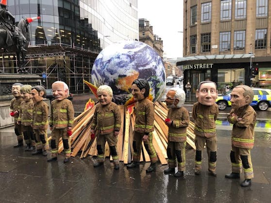 Im Zentrum von Glasgow demonstrierten am Freitag Umweltschützer gegen ambitionslose Klimapolitik. Sie zeigten Politiker, die versuchen, die brennende Welt mit viel zu kleinen Wasserbehältern zu löschen.