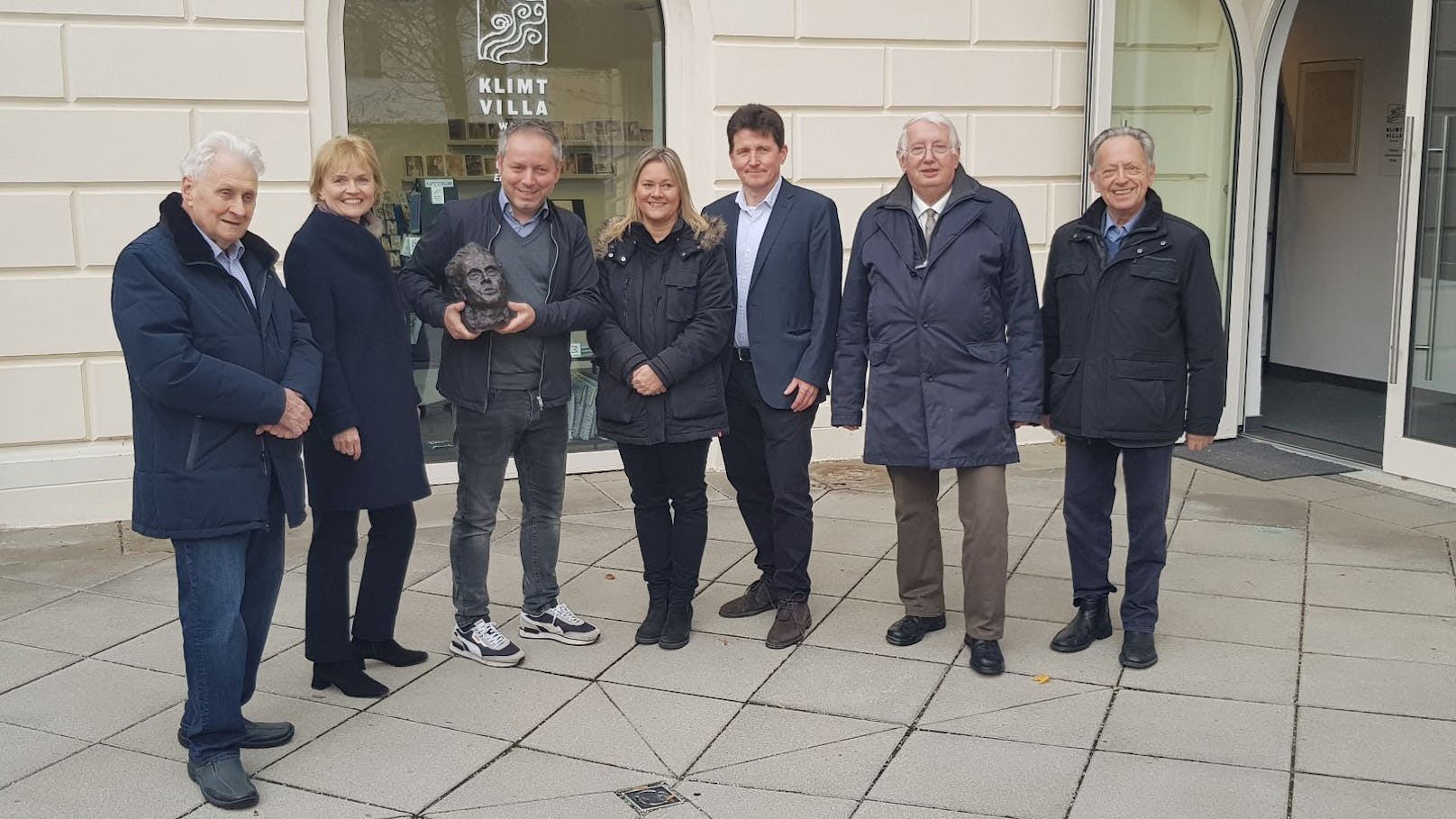 Großes Empfangskommitee für eine kleine Metallbüste: (v.l.n.r.) Kurator Rudolf Wawra (Bezirksmuseum Hietzing), Bezirksvorsteherin Silke Kobald, der glückliche Finder und Geschäftsführer der Klimt Villa Baris Alakus, Bezirksinspektorin Bettina Panczuk, Oberstleutnant Günter Steinwendtner (beide LKA Wien – Außenstelle Wien-Mitte, Ermittlungsbereich Diebstahl), Museumsleiter Ewald Königstein (Bezirksmuseum Hietzing), und der frühere Bezirksvorsteher und Präsident des Bezirksmuseums Hietzing Heinz Gerstbach nahmen das Kunstwerk entgegen.